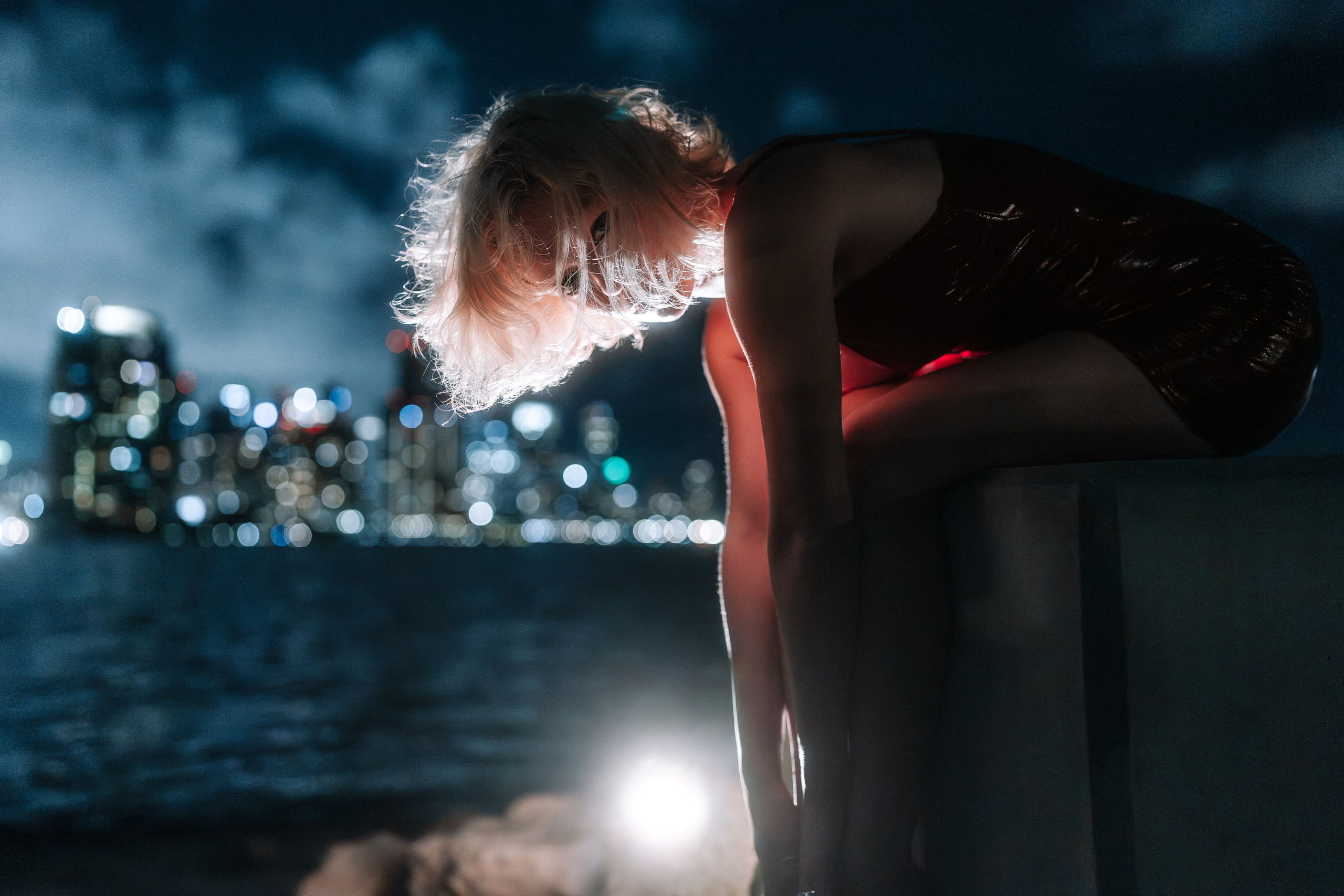 The model sits at the water’s edge, hands relaxed. Light draws focus to the face.