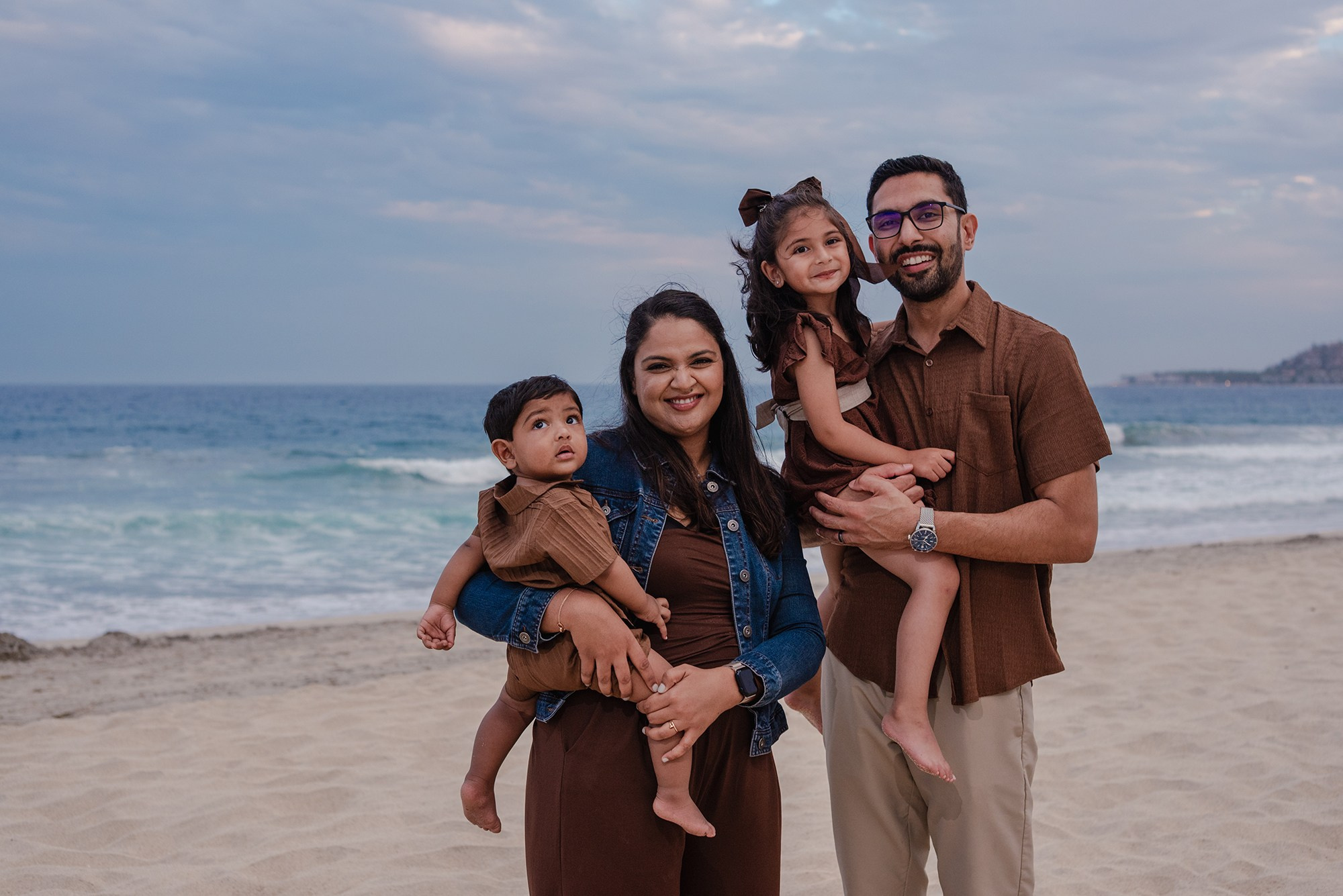Family of four posing together on the beach at Hyatt Ziva Los Cabos to close the session