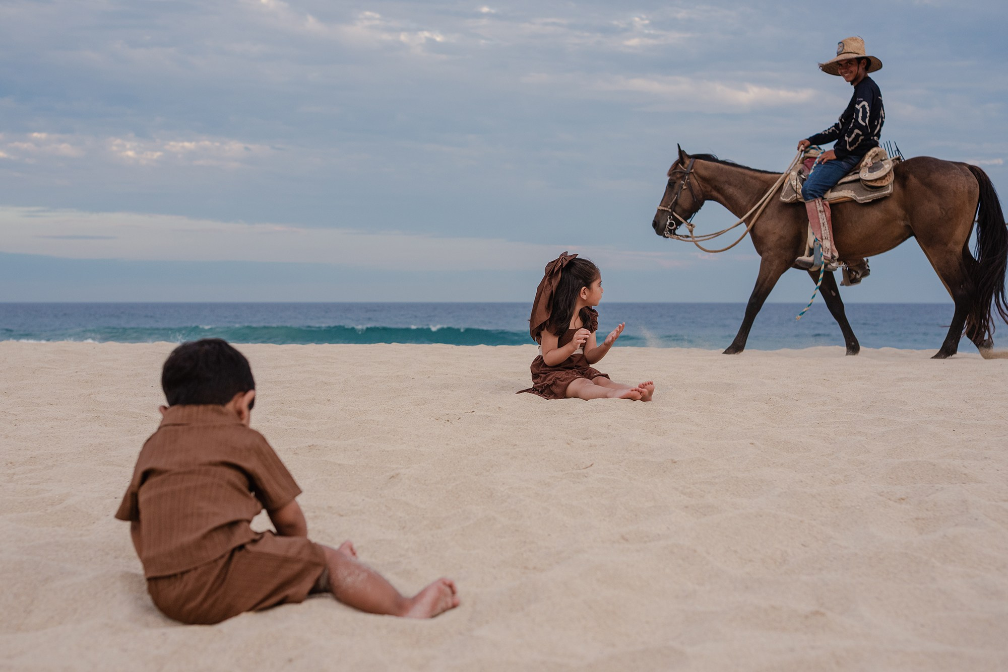Family watching a horseback rider pass along the shoreline at Hyatt Ziva Los Cabos