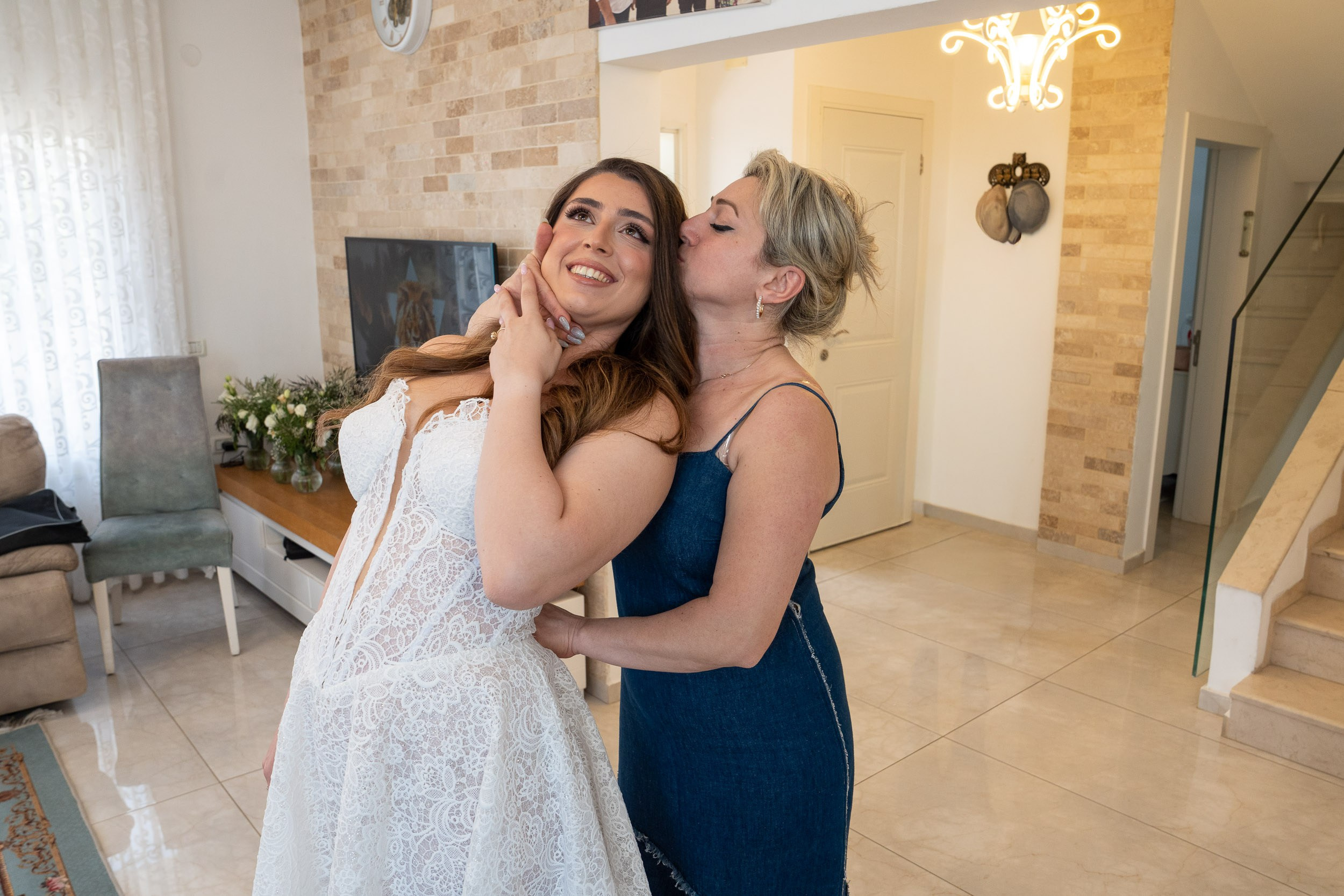 Bride Tzipi receiving a loving kiss from her mother during morning preparations in Hadera, Israel