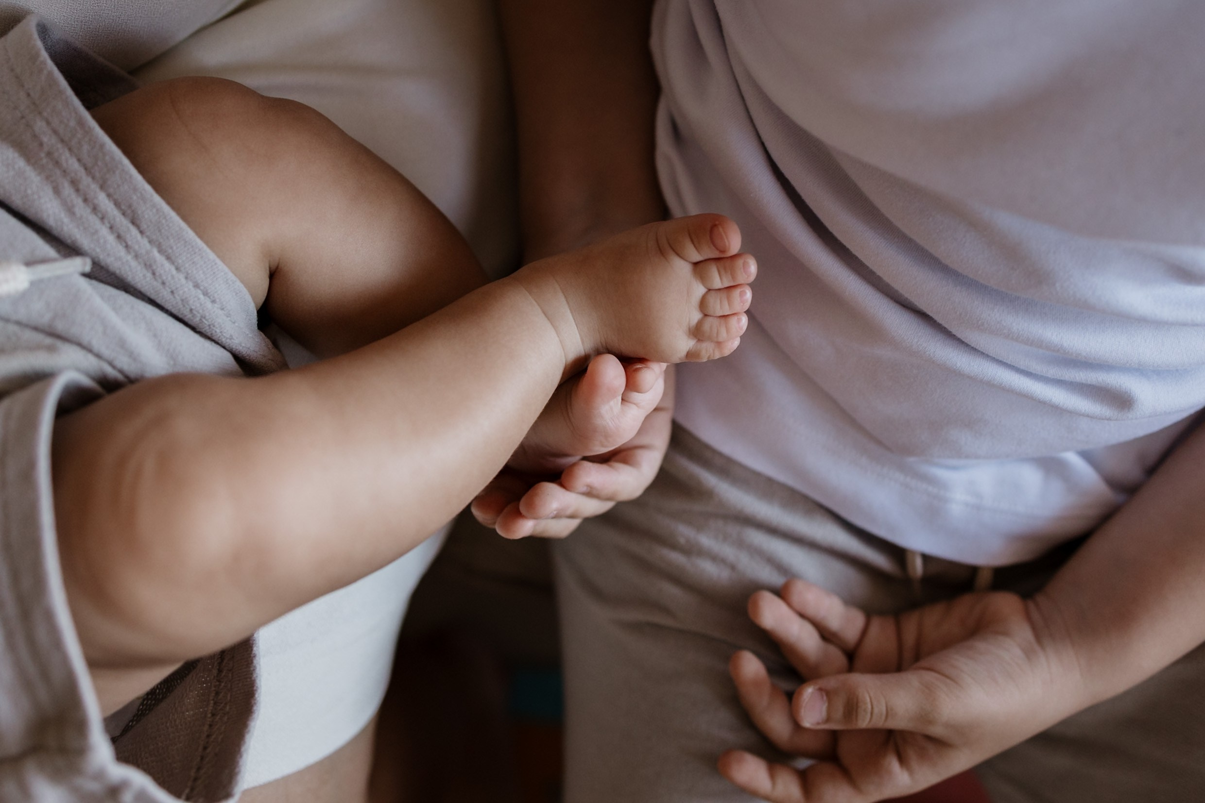 Detalhe pezinho do bebe e mão do irmão mais velho