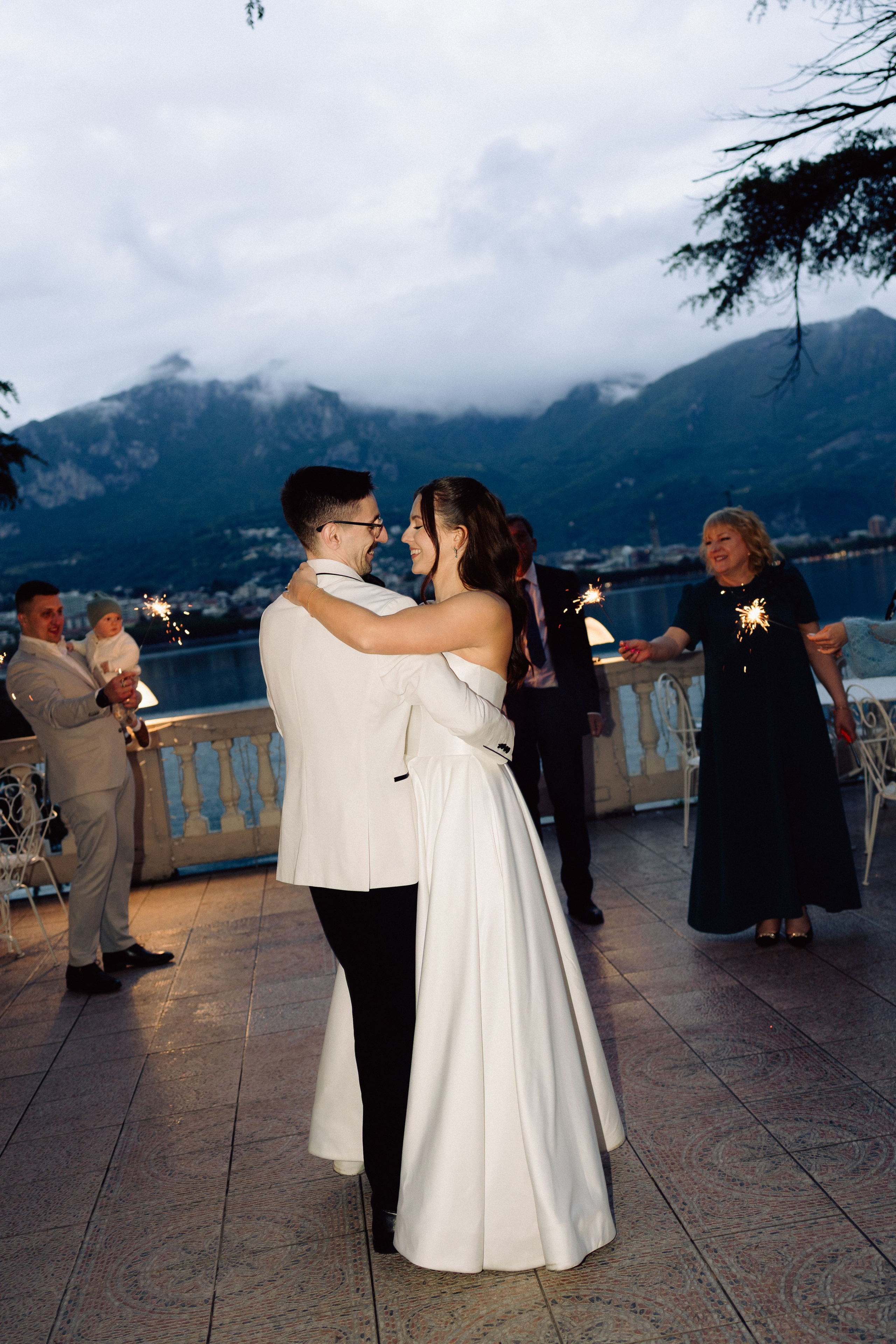 Bride and groom dancing on a terrace overlooking Lake Como at sunset