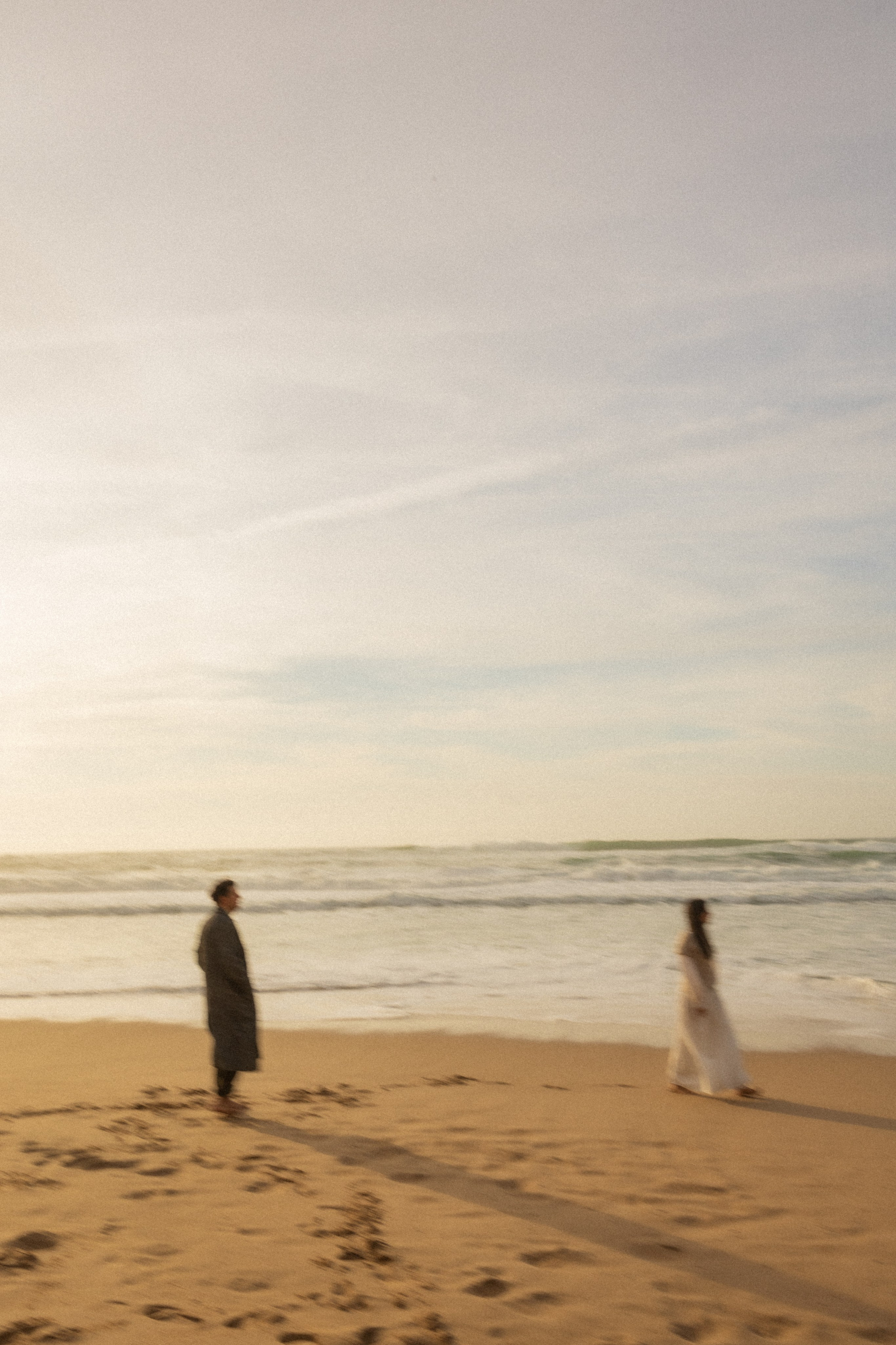 Couple holding hands and walking through a picturesque coastline in Portugal.