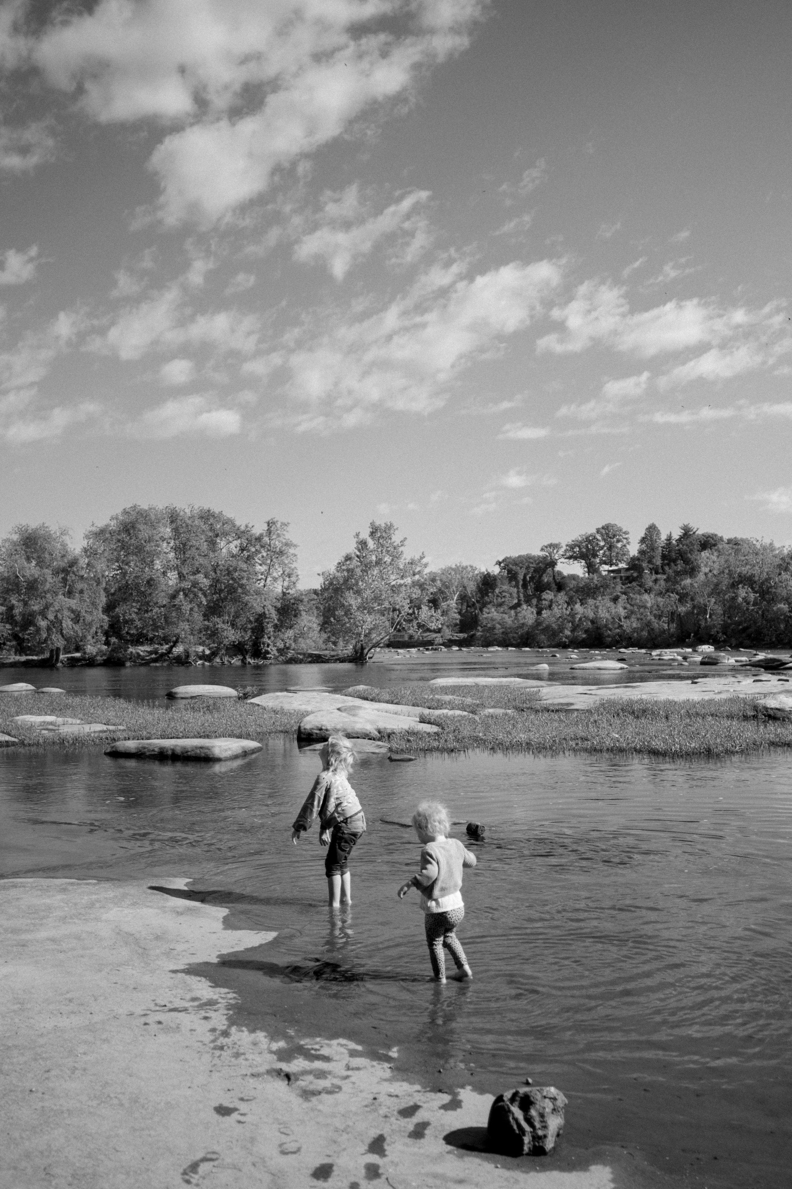 A fun, active lifestyle family photo session featuring a family walking barefoot through the shallow river rapids