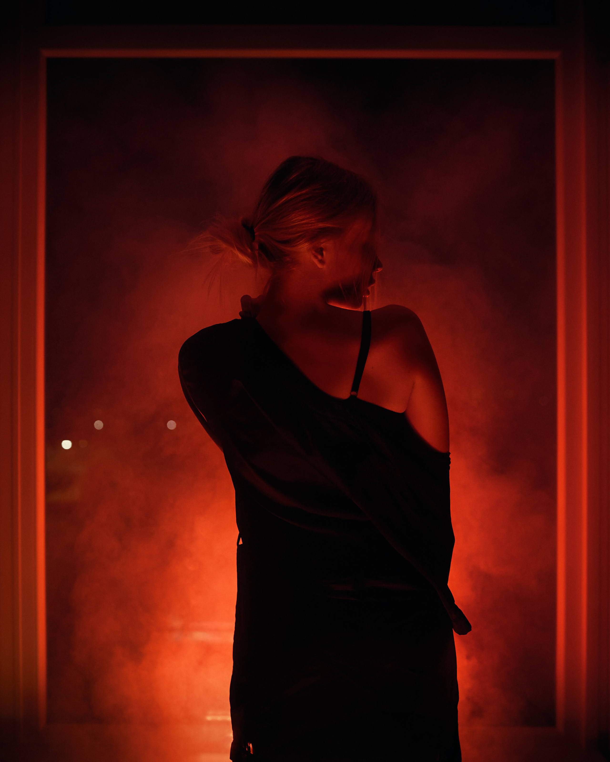 A dramatic portrait of a woman lit by warm, glowing light with a smoky background, exuding elegance and mystery.