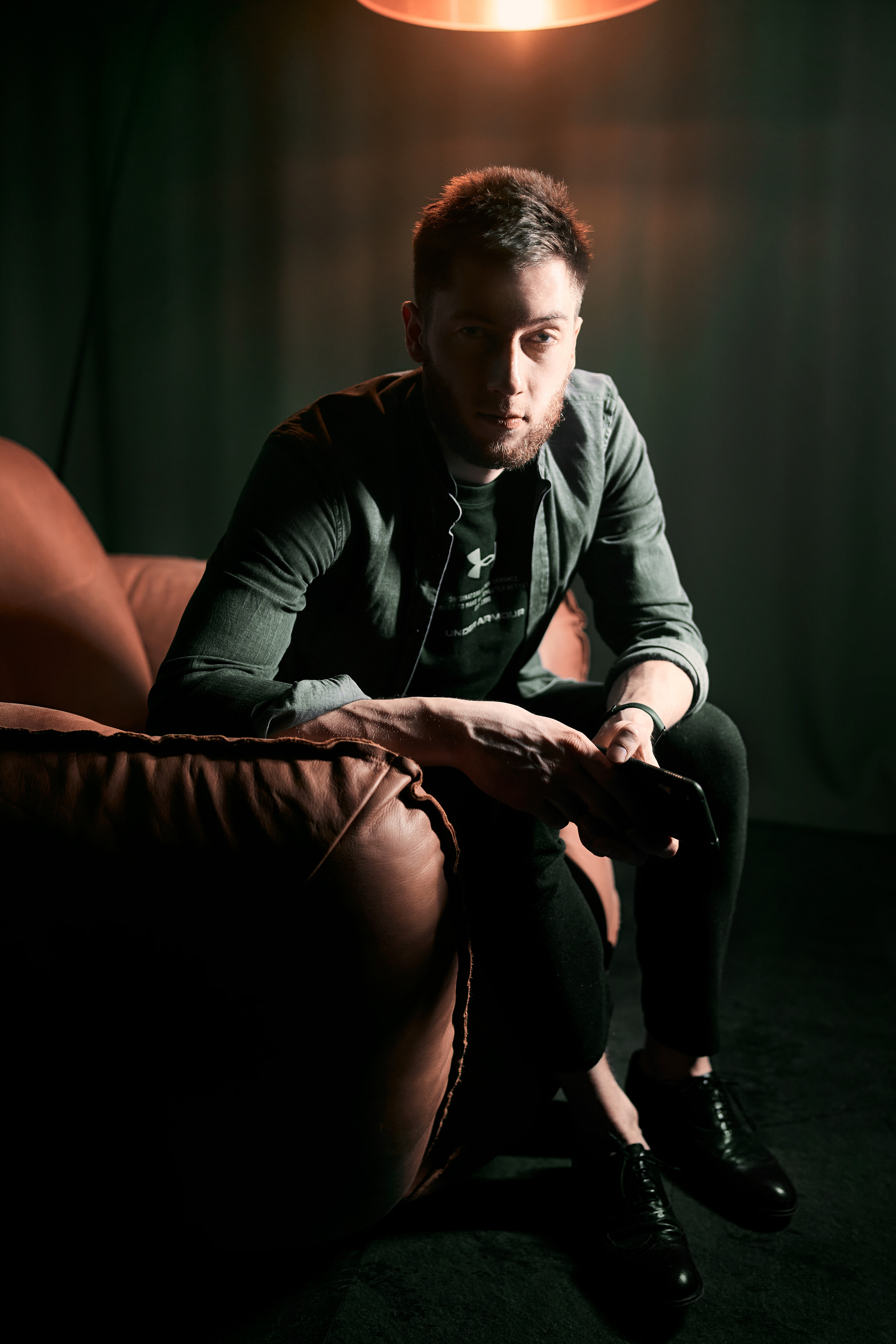A man in a tailored suit sitting in a leather chair, staring thoughtfully, with warm lighting enhancing the composition