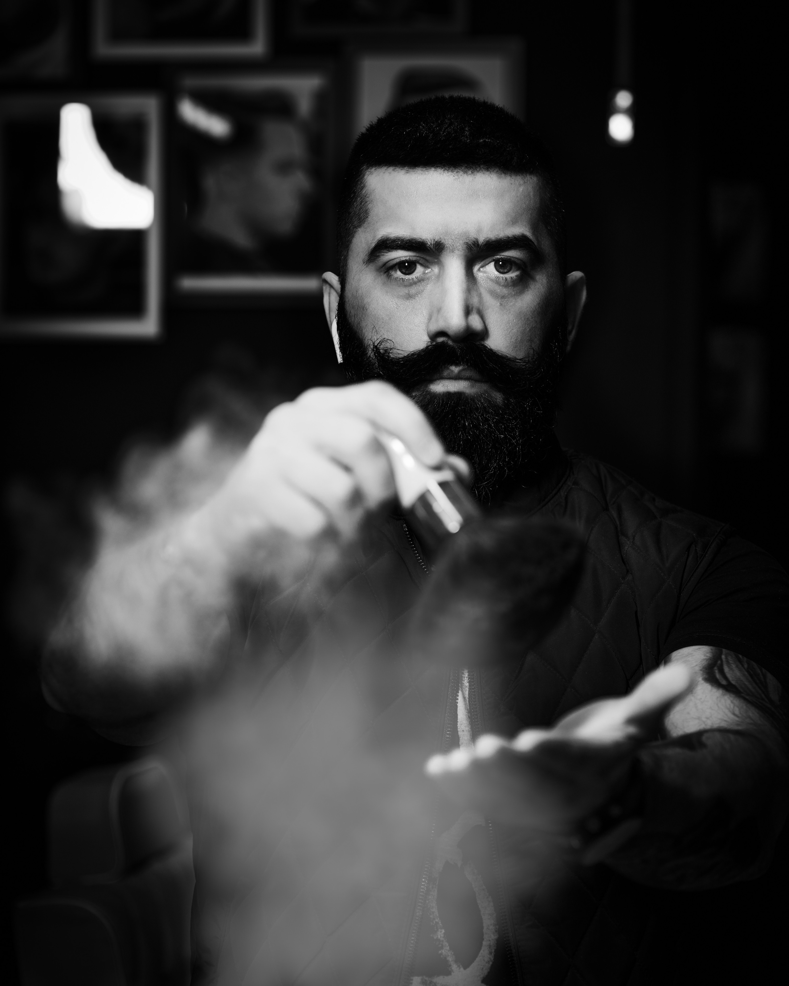  A black-and-white portrait of a barber , his face partially lit for a moody and artistic effect.