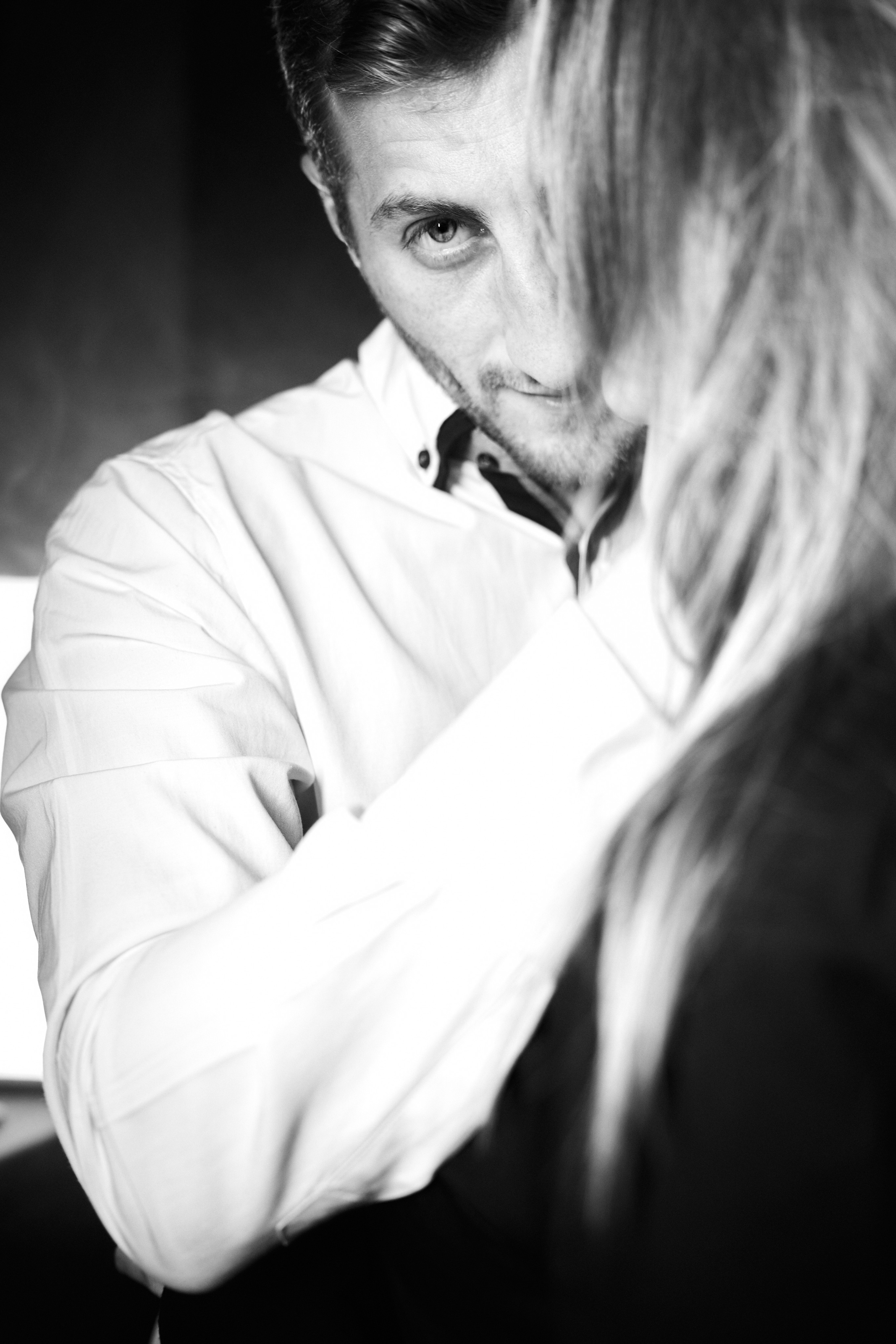 A close-up black-and-white portrait of a man embracing a woman, with a soft, emotional tone.