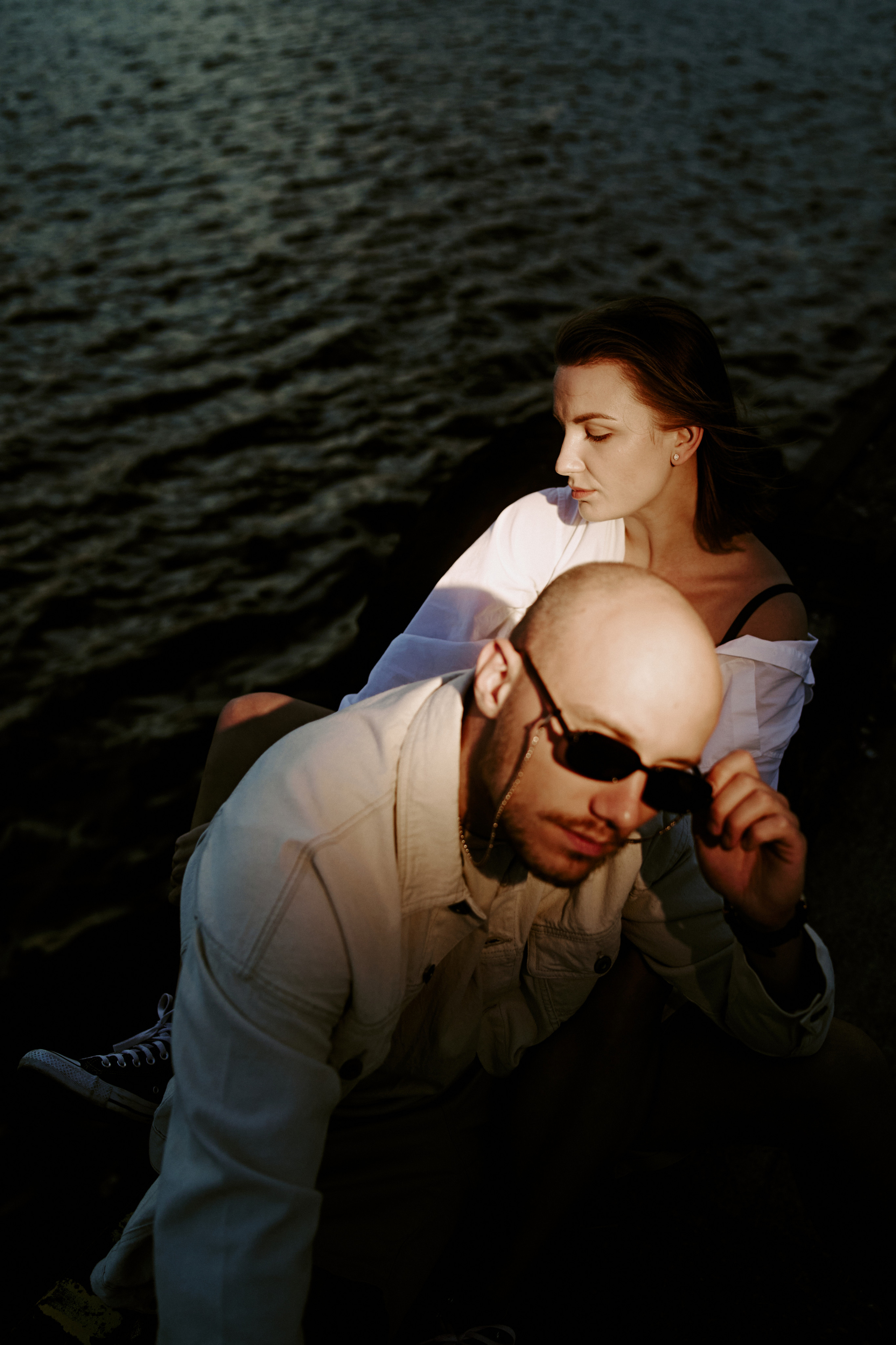 A couple embracing on a boat, surrounded by dark waters, evoking a sense of intimacy and adventure.