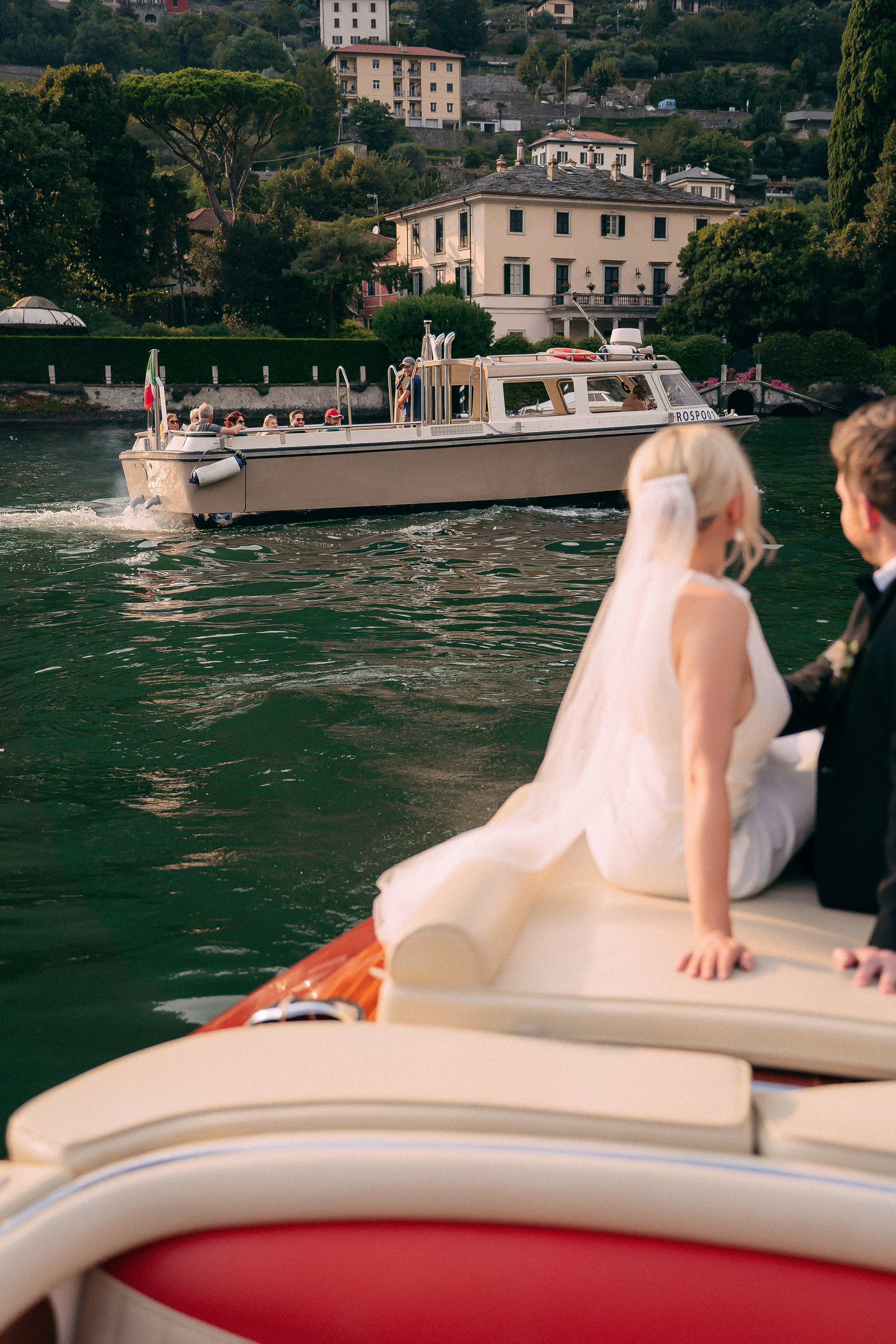 Bride sitting on the boat with the lakeside village at Villa Lario, Lake Como, Italy