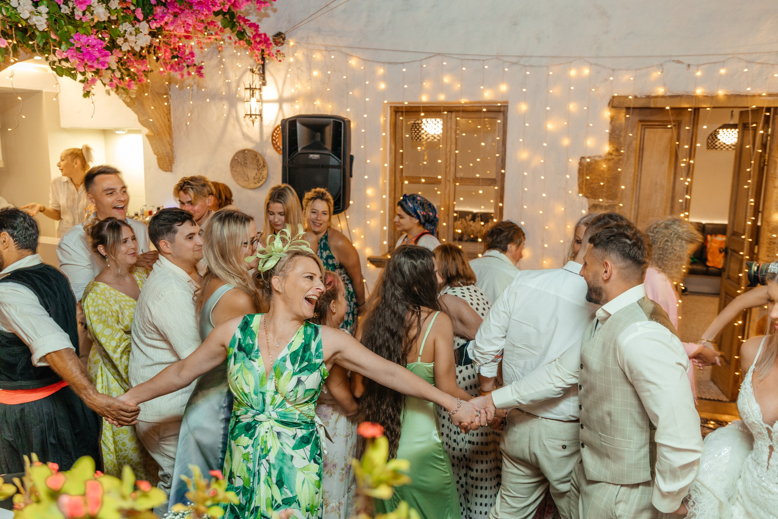 Group of guests dancing and celebrating at the wedding party in a traditional Greek restaurant in Lindos, with the couple joining in the fun.