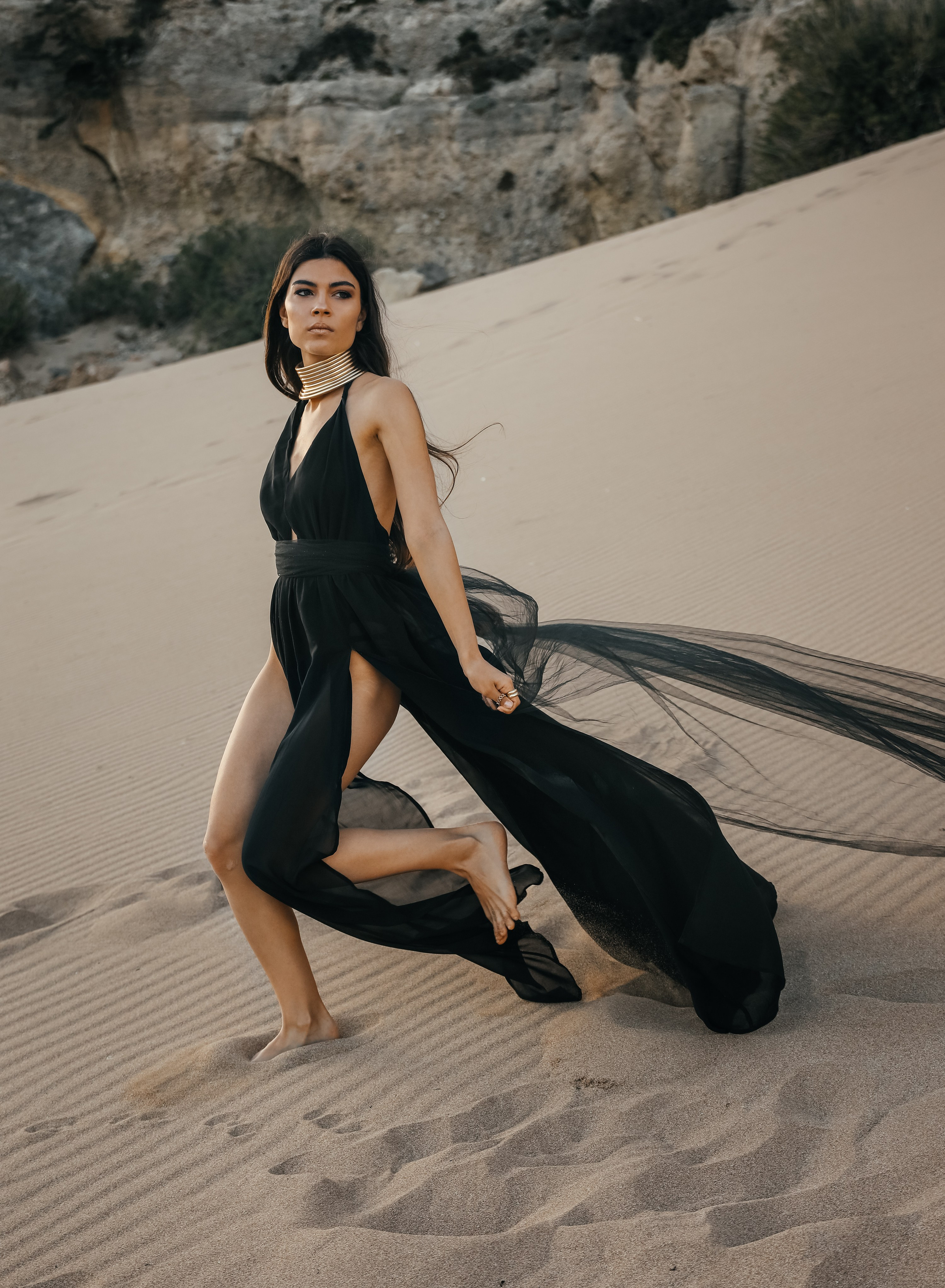 A chic girl in a black dress running in the Desert. Rhodes island, Greece