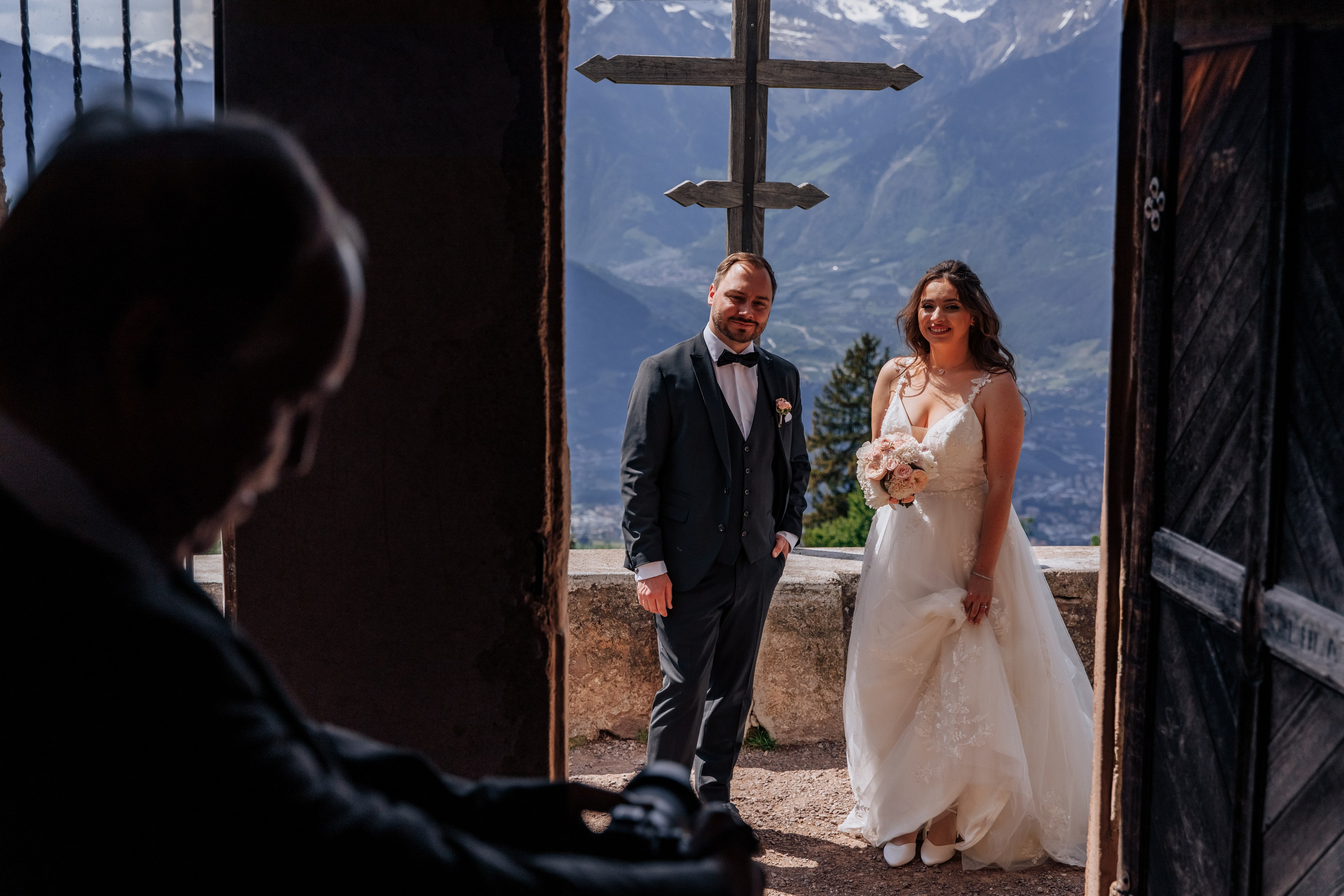 Der Bräutigam und die Braut lächeln und schauen neugierig in die Kirche, voller Vorfreude auf ihre Zeremonie.