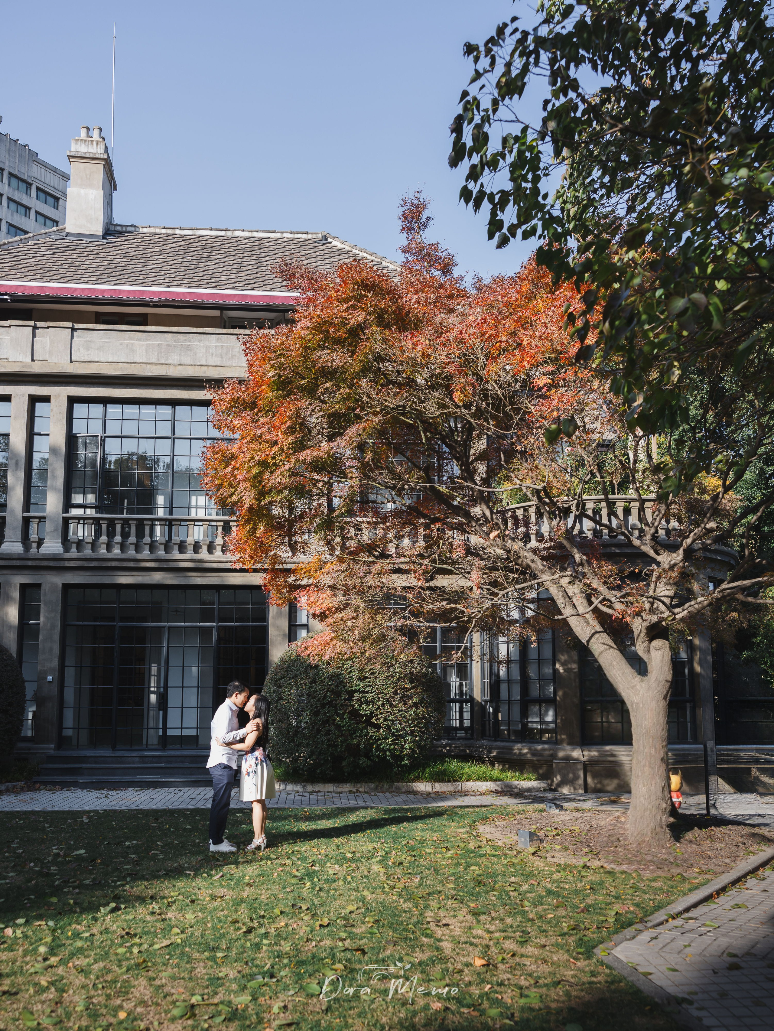 Couple sharing a quiet kiss beneath maple trees in Shanghai's autumn