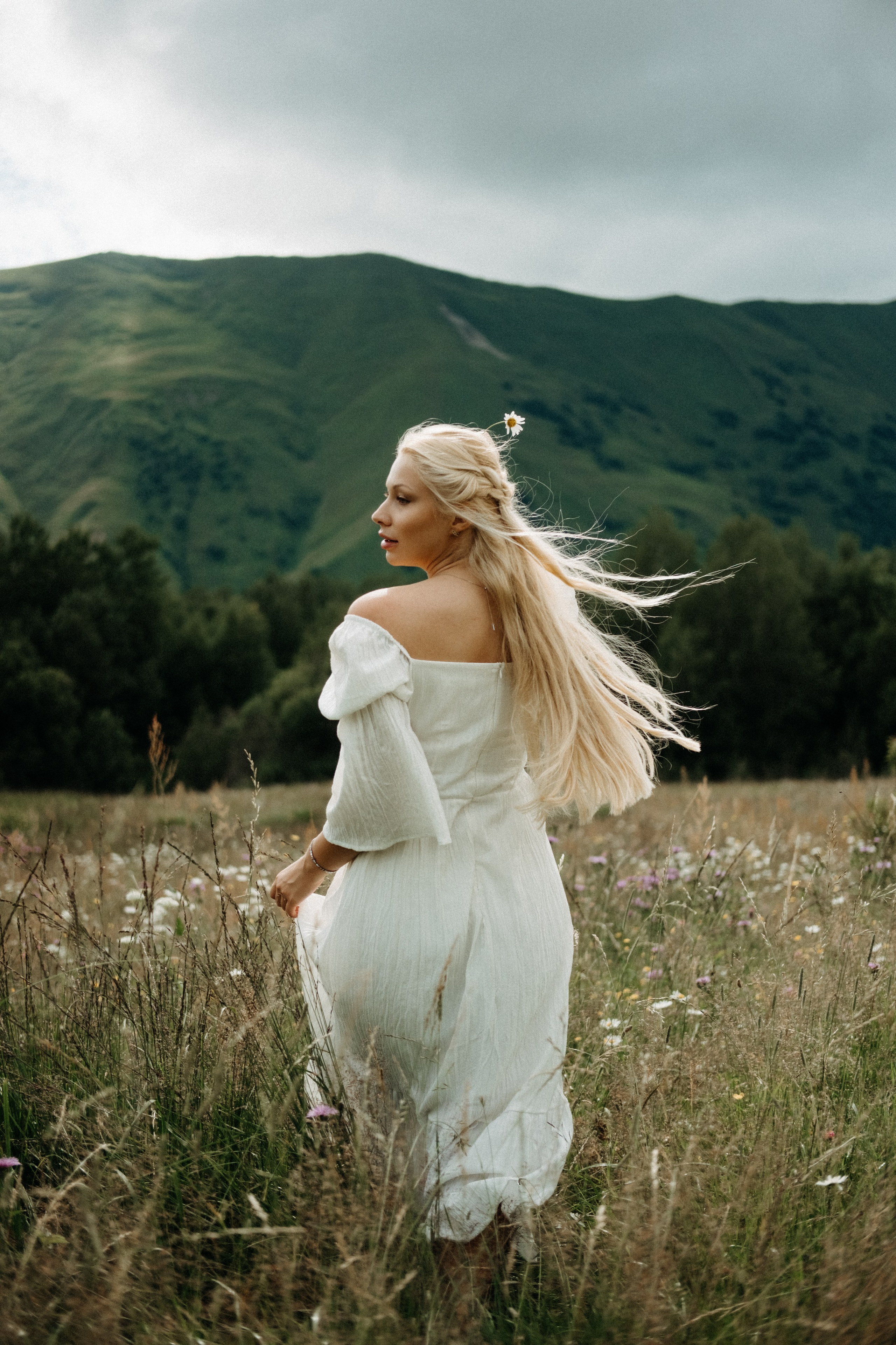 Woman walking through meadow in summer mountains