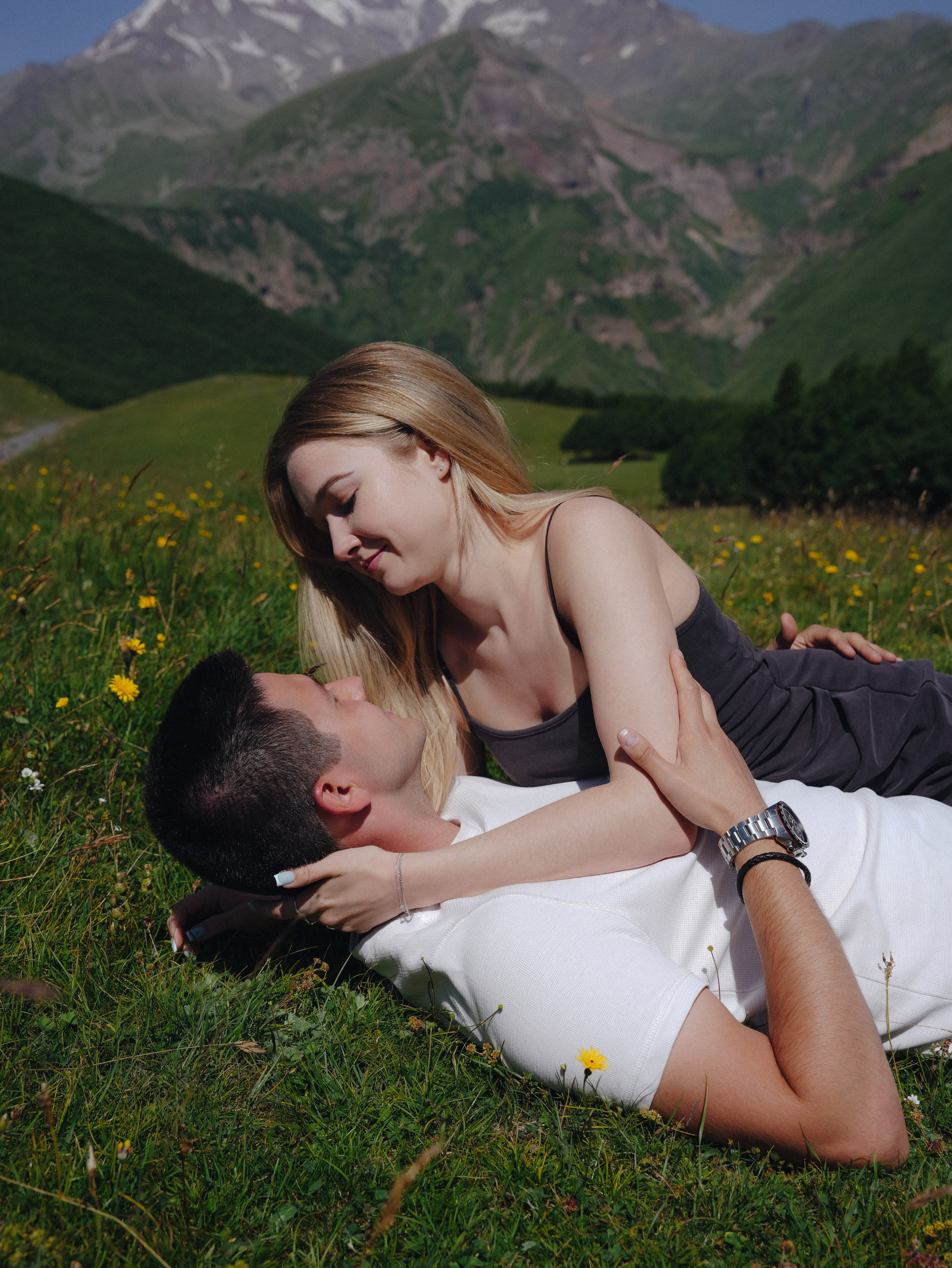 Couple lying on grass during summer mountain photoshoot