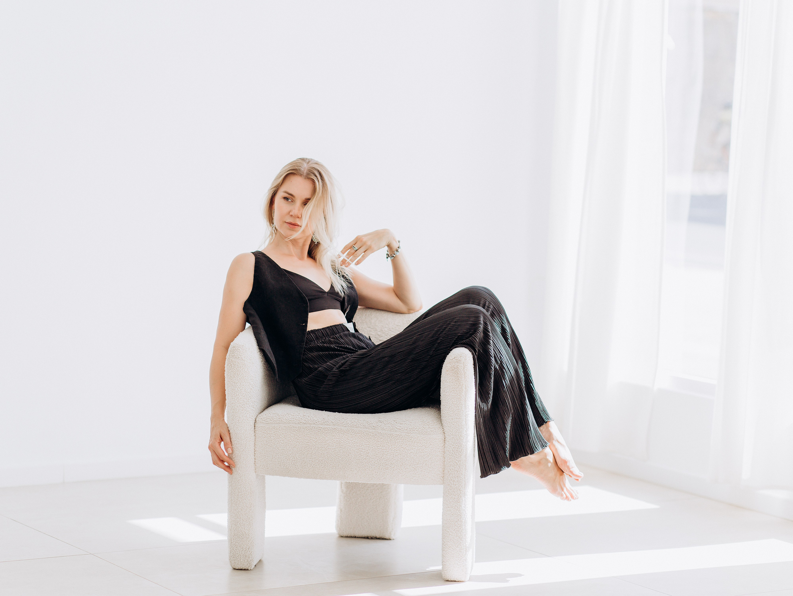 Элегантный женский портрет в расслабленной позе на белом кресле, снятый в студии с естественным светом в Валенсии, Испания — идеально для тех, кто ищет вневременную женскую портретную фотосессию в Валенсии и по всей Испании.