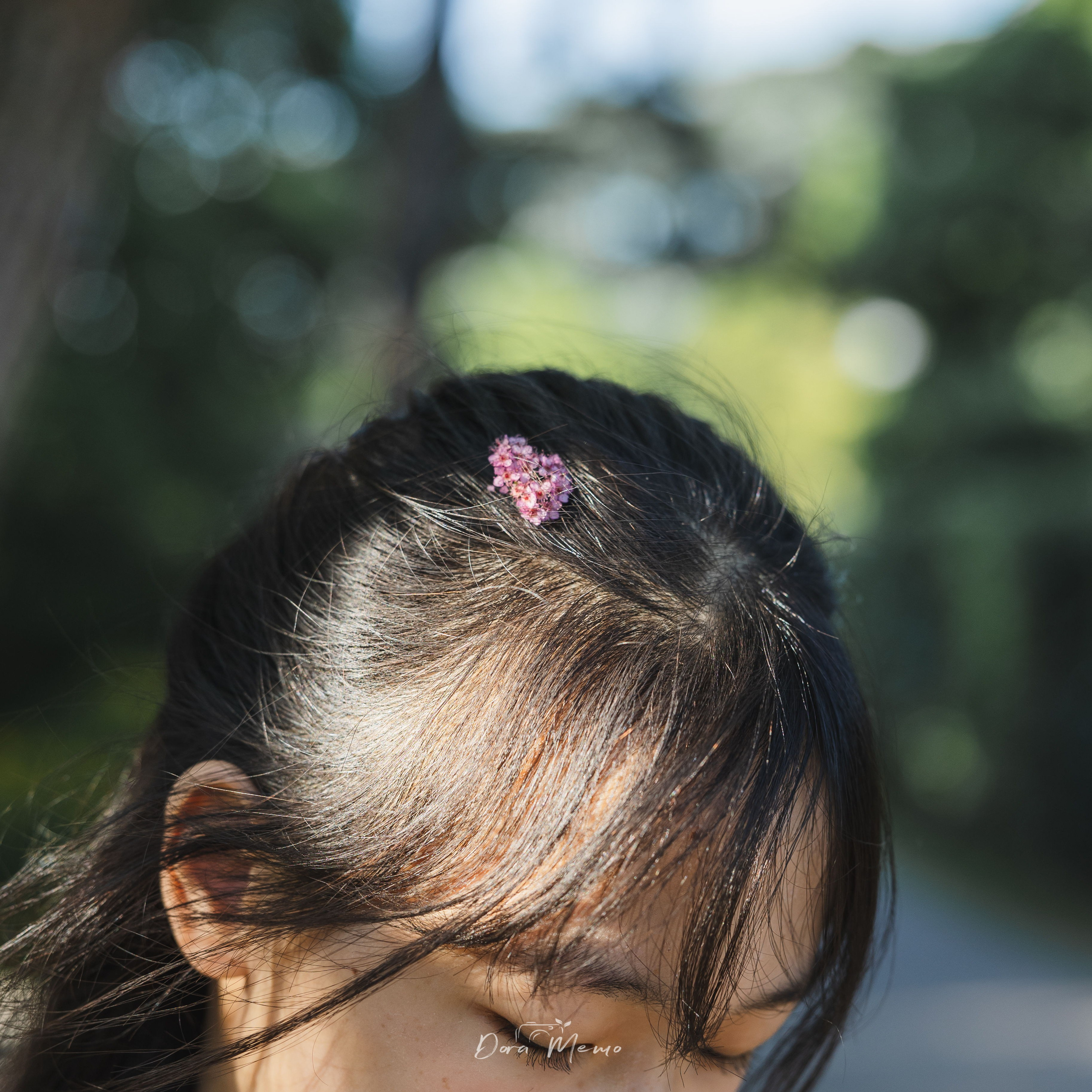 Close-up detail, a small flower tucked in her hair | Soft detail of a flower in a girl's hair, natural light portrait