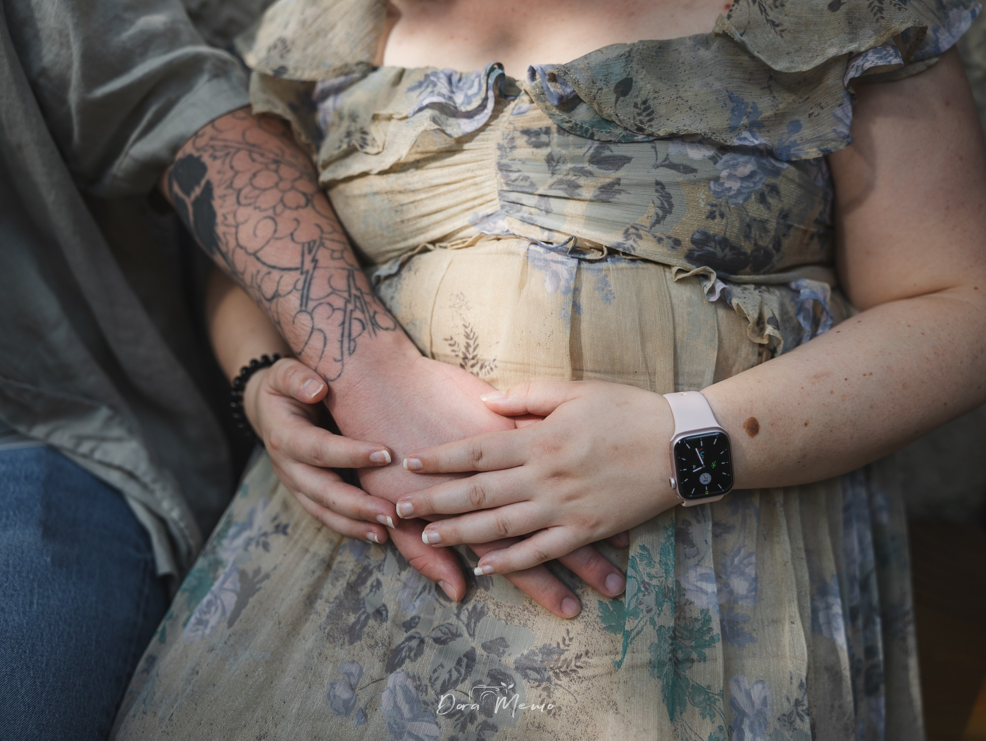 Close-up of hands resting on a pregnant belly during a natural maternity photography session.