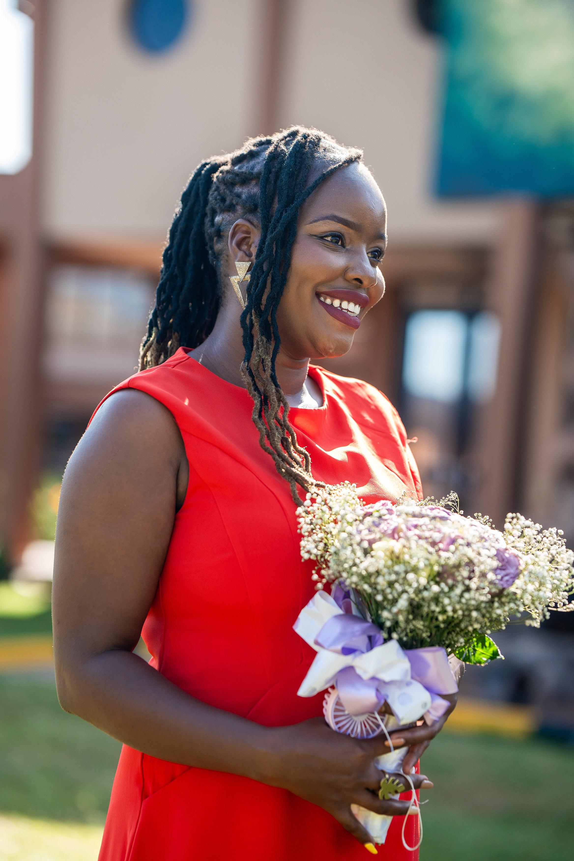 A portrait of a lady in an orange dress carrying a bouquet of flowers