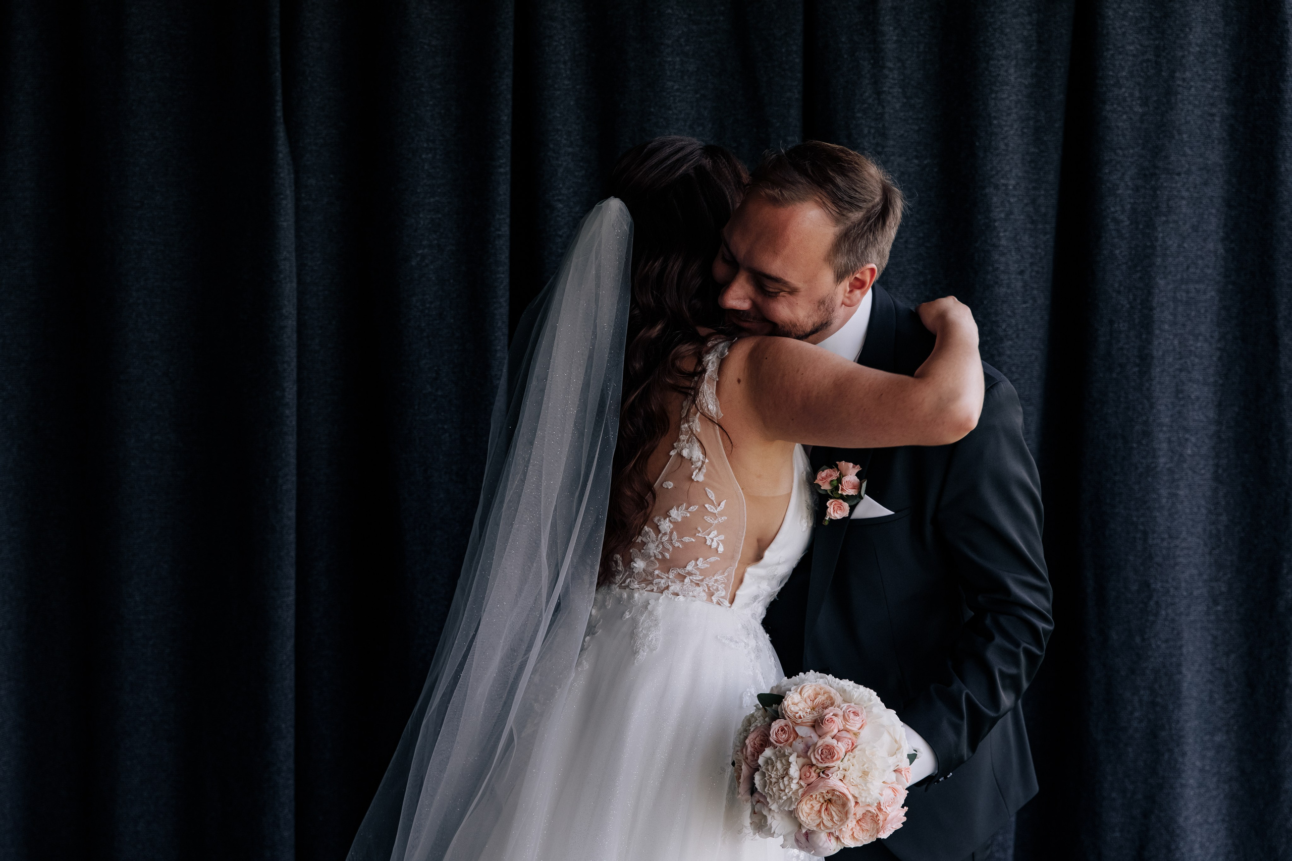 Der Bräutigam umarmt die Braut in einem emotionalen Moment der Hochzeit. Ein Ausdruck von Liebe und Zuneigung.