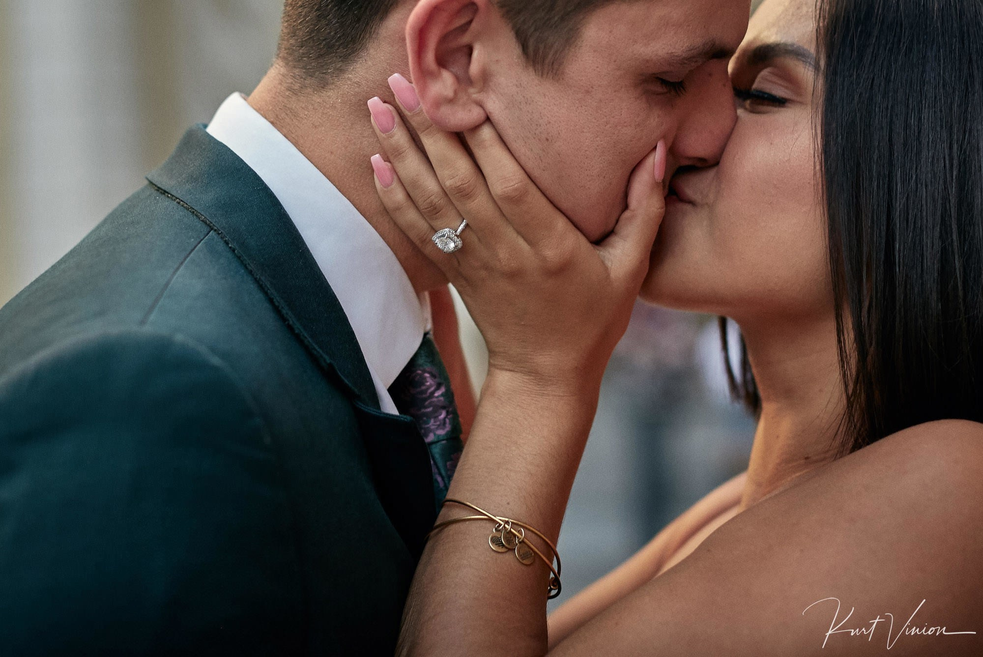 Woman showing diamond engagement ring kissing partner in front of St. Vitus Cathedral in Prague.