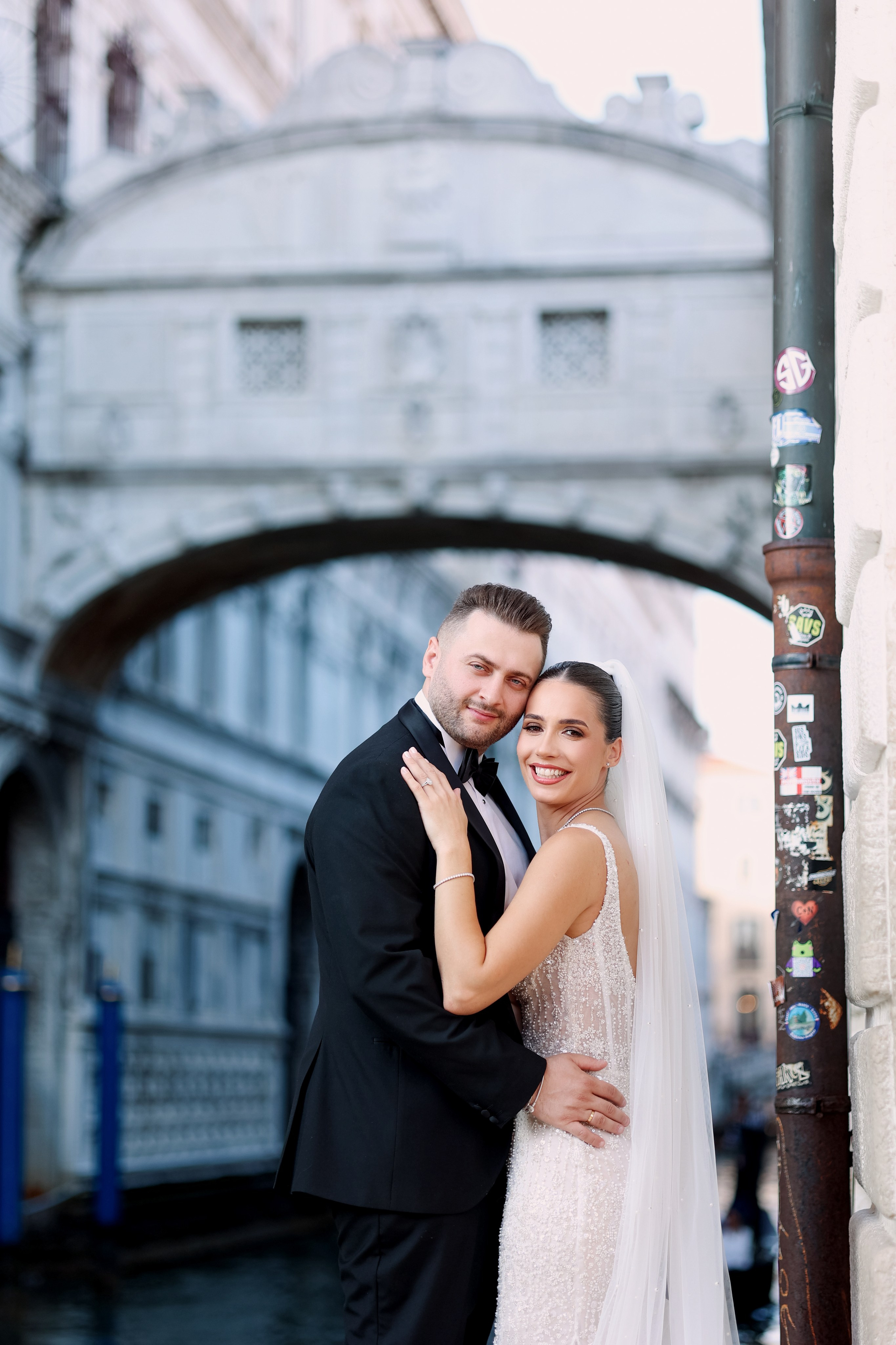 Romantic moment of a wedding couple by the Bridge of Sighs and gondolas on the canals of Venice