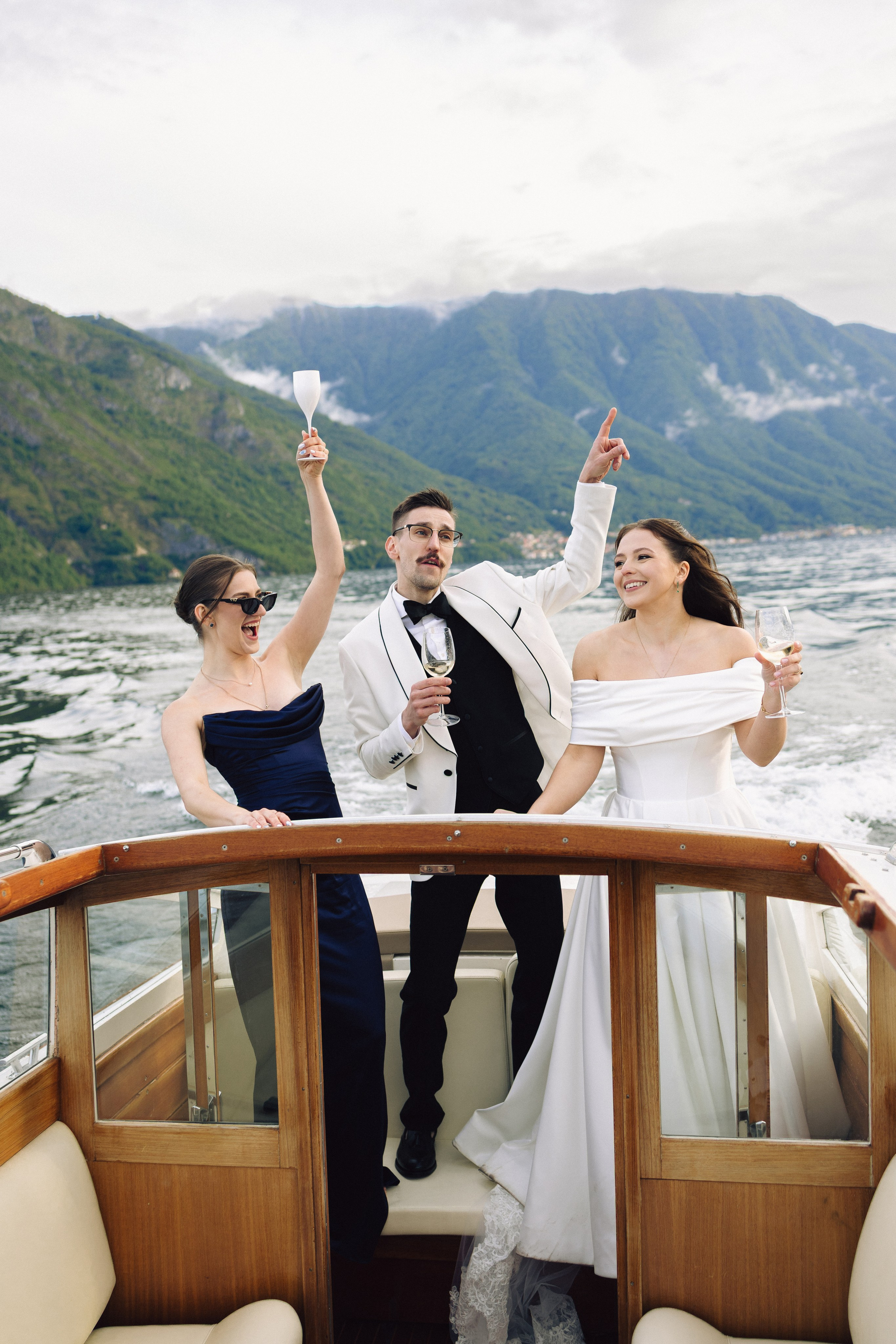 Bride, groom and their guest celebrating with champagne on a boat in Bellagio