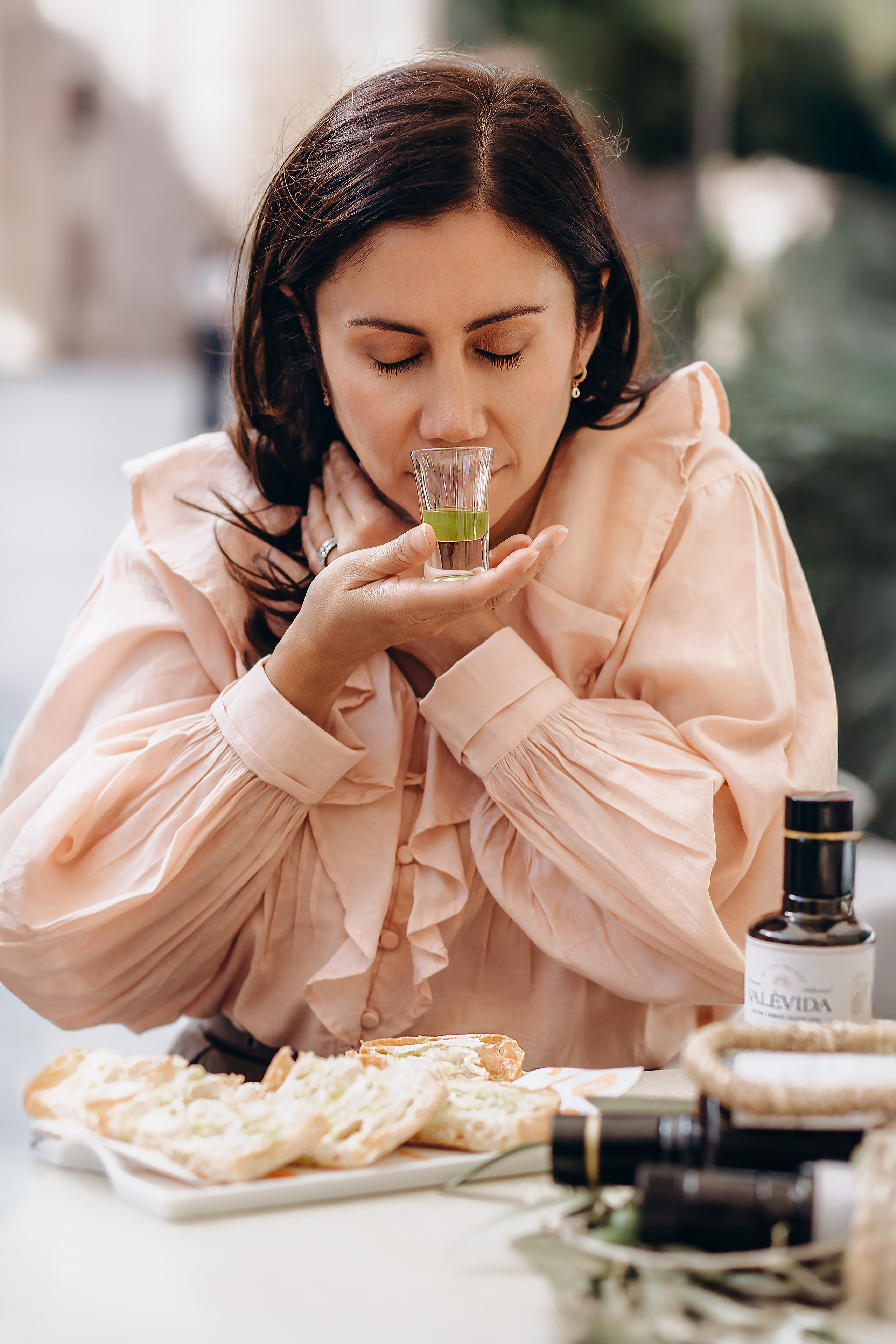 Close-up brand photography of a woman savoring the aroma of extra virgin olive oil during a tasting session in Valencia, Spain — ideal visual content for product, branding, and lifestyle photoshoots that capture Mediterranean authenticity and gourmet experience.