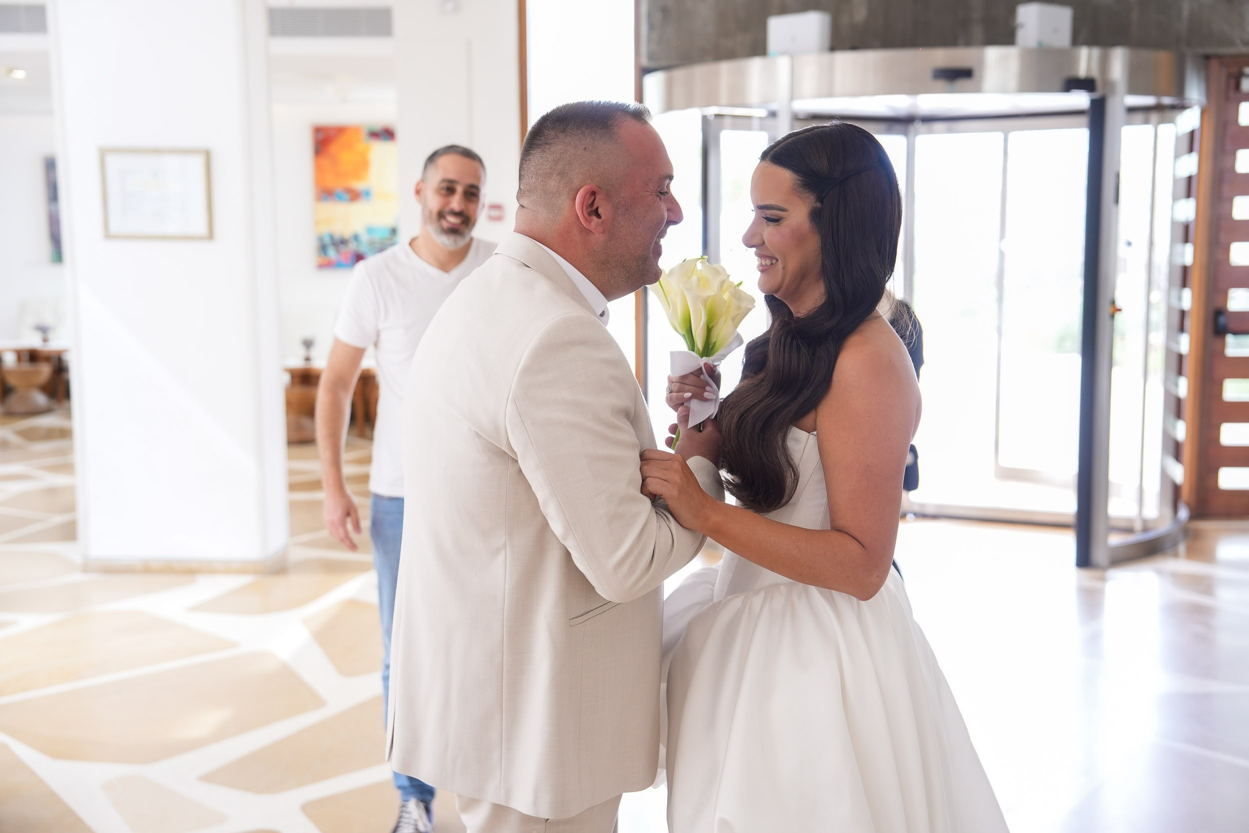 Bride Shani holding a calla lily bouquet and laughing with groom David during their first look in Zikhron Ya'akov, Israel