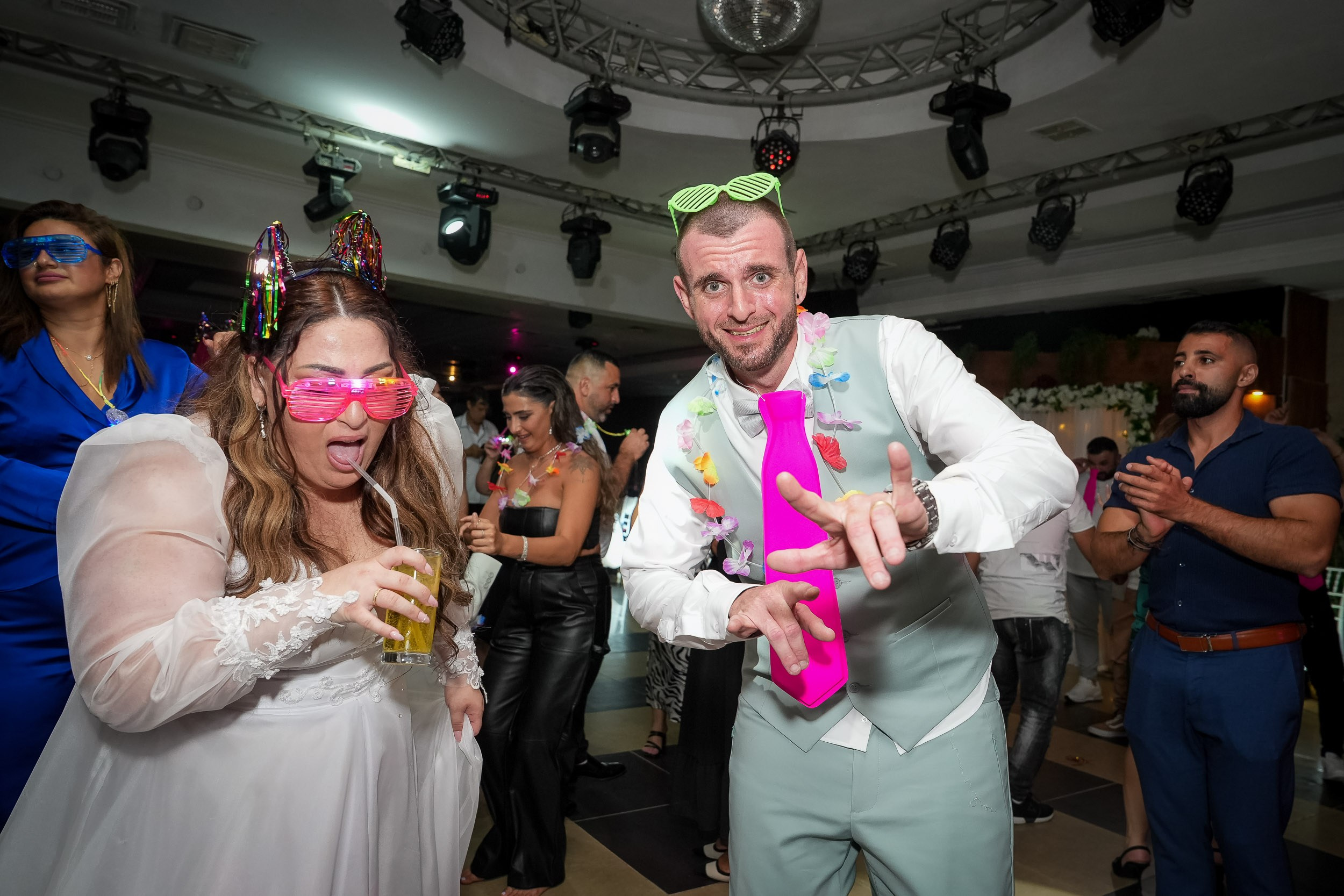 Ella and Matan dance together with neon accessories during the wedding party