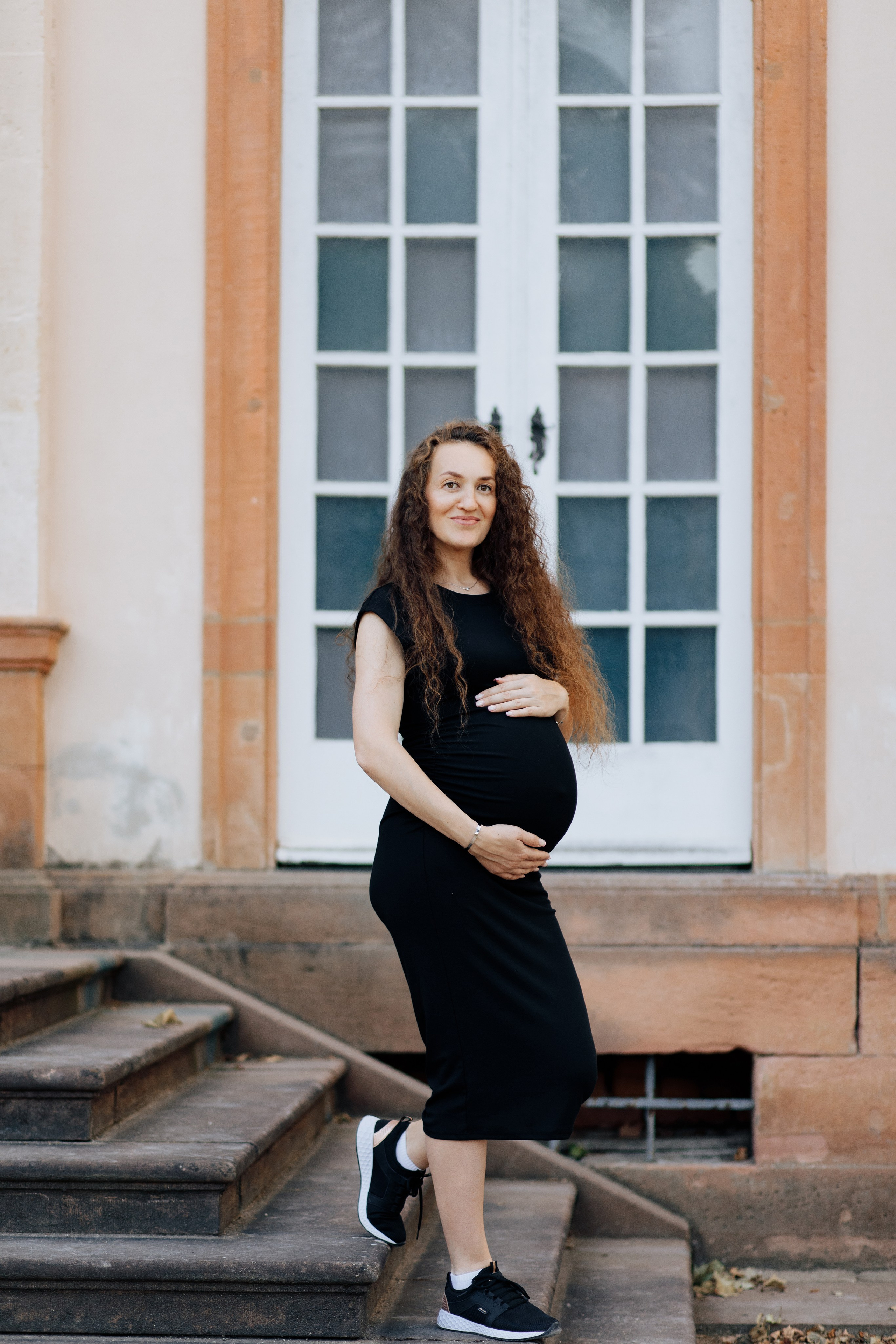 Schwangere Frau geht die Treppe im Park Schönbusch in Aschaffenburg hinunter.