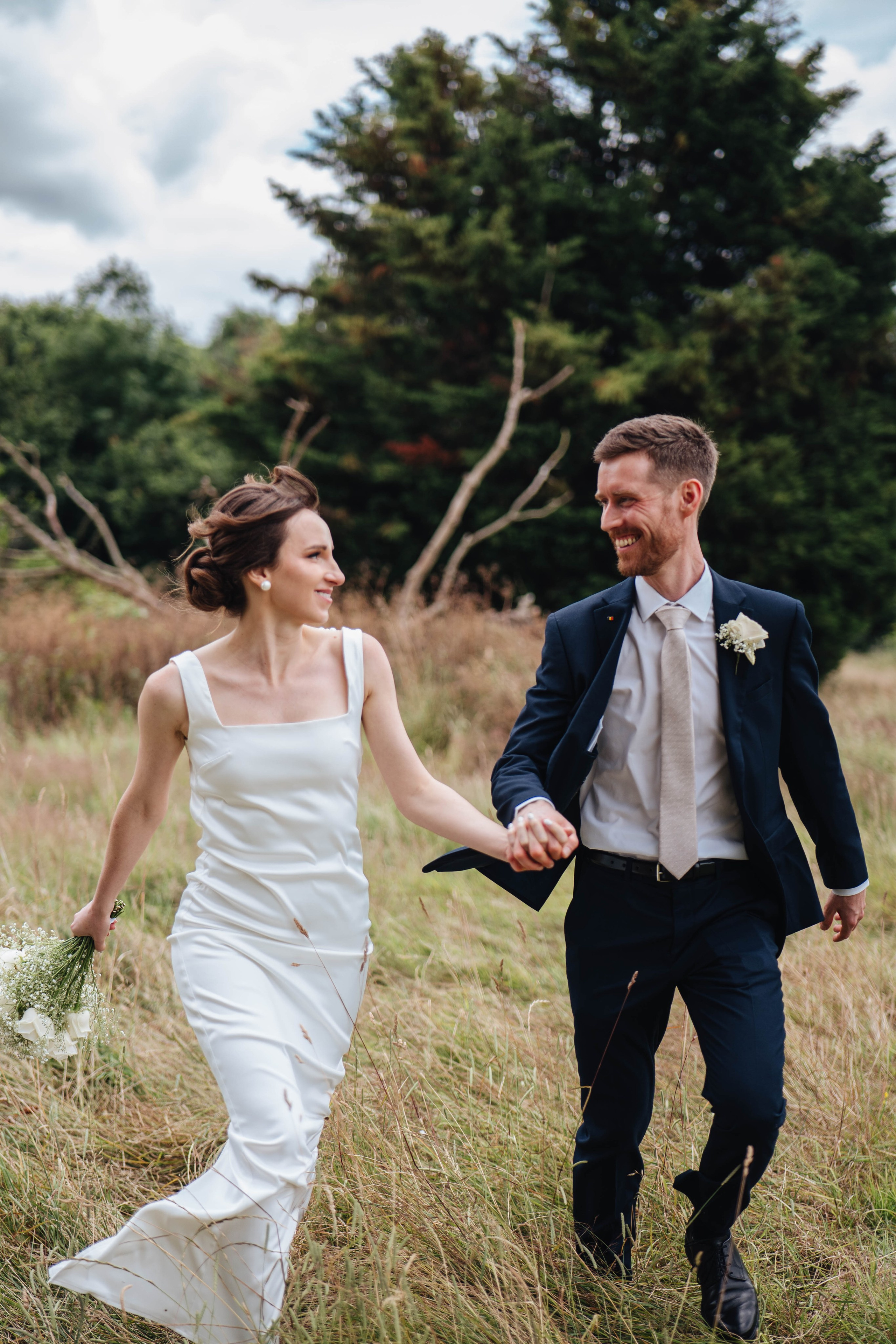 bride and groom running while holding hands and looking at each other