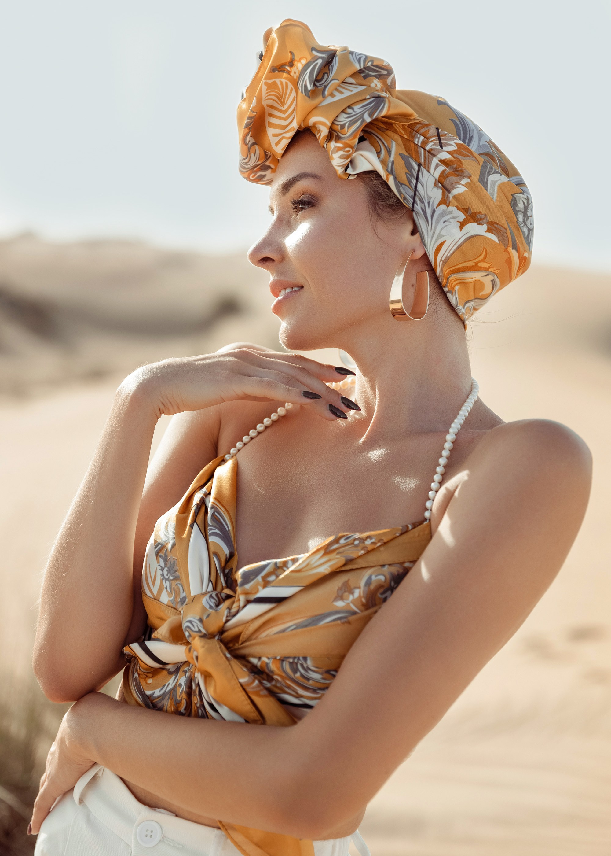 A beautiful woman poses in the desert, her elegance contrasting with the rugged, untamed beauty of the sandy surroundings. Dubai, United Arab Emirates