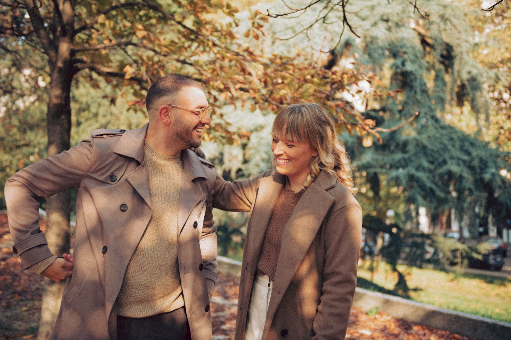 A warm and candid autumn couple photoshoot filled with natural smiles and soft golden light. The couple enjoys a relaxed walk through a park covered in fall leaves, creating joyful and spontaneous moments. Perfect inspiration for lifestyle couple photography, natural poses, and warm fall aesthetic ideas for a romantic photoshoot. autumn couple photoshoot, fall couple session, candid couple photography, lifestyle couple photos, natural couple poses, fall aesthetic photoshoot, warm tones photography, outdoor couple session, romantic autumn inspiration, golden hour fall photos