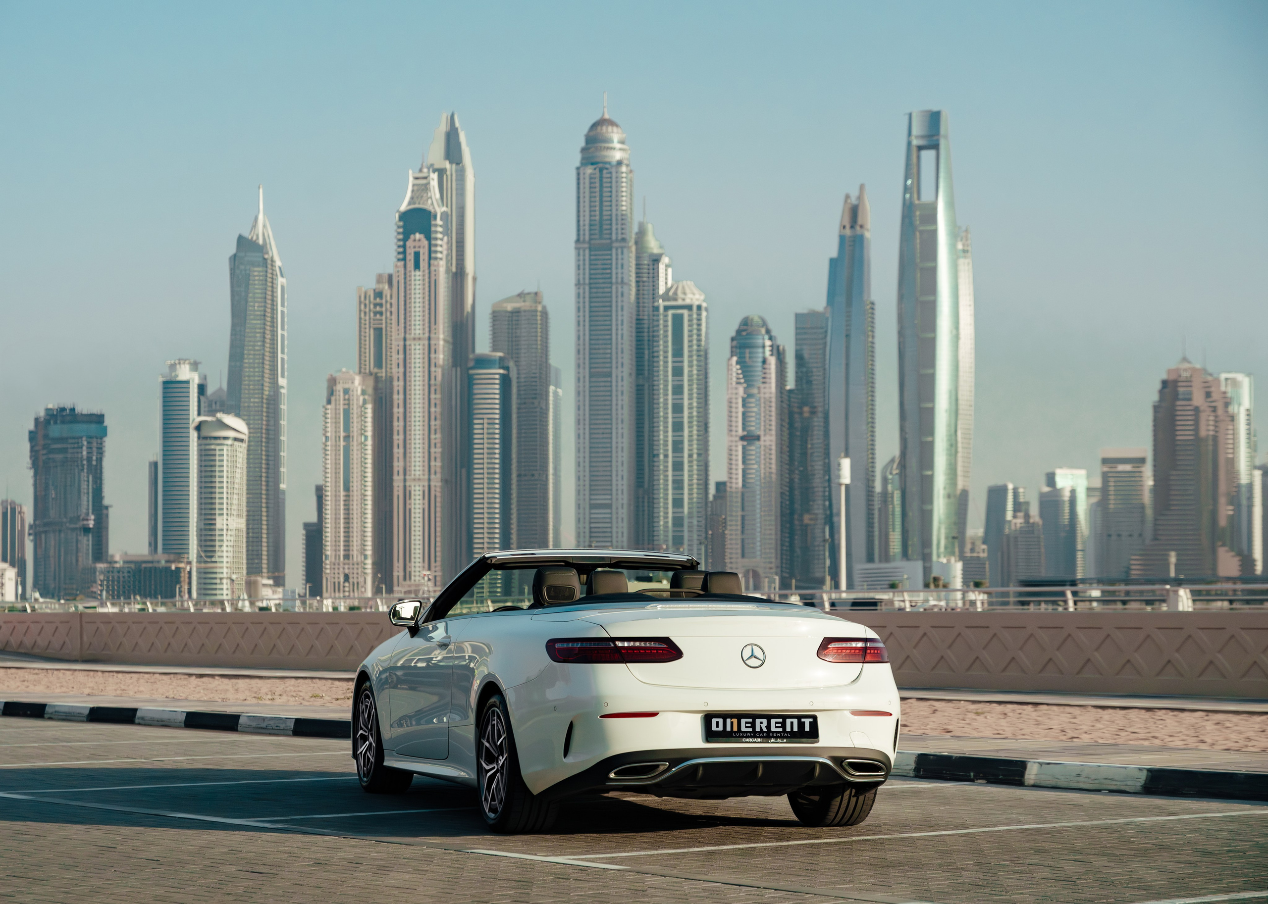 A white Mercedes is parked in the back with the roof open during sunset.