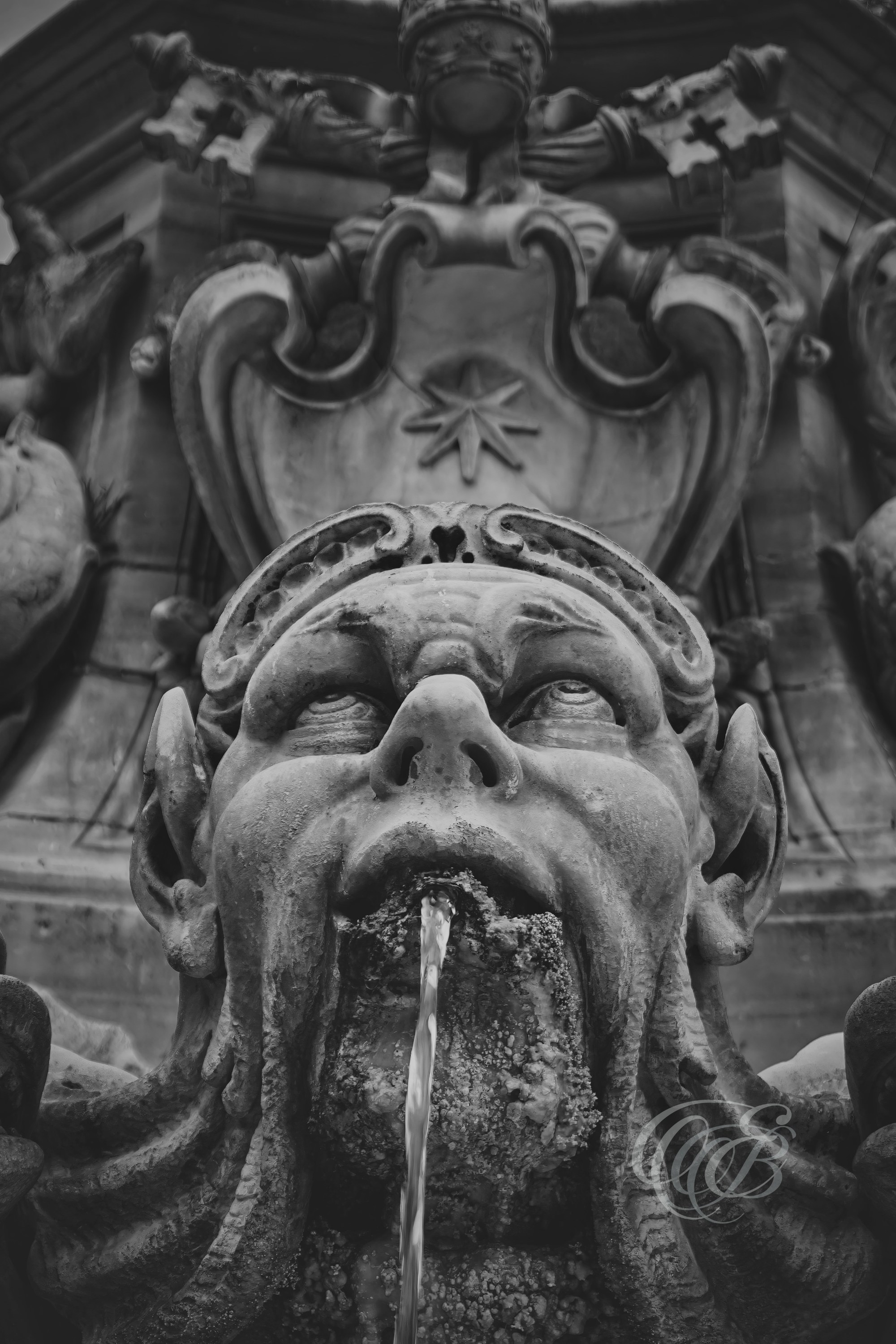 Rome Italy – Close-up detail of a grotesque sculptural face from the Fontana del Pantheon, carved stone ornamentation captured in black and white fine art photography. Rome, Italy – photography by Eduardo Bartoli.