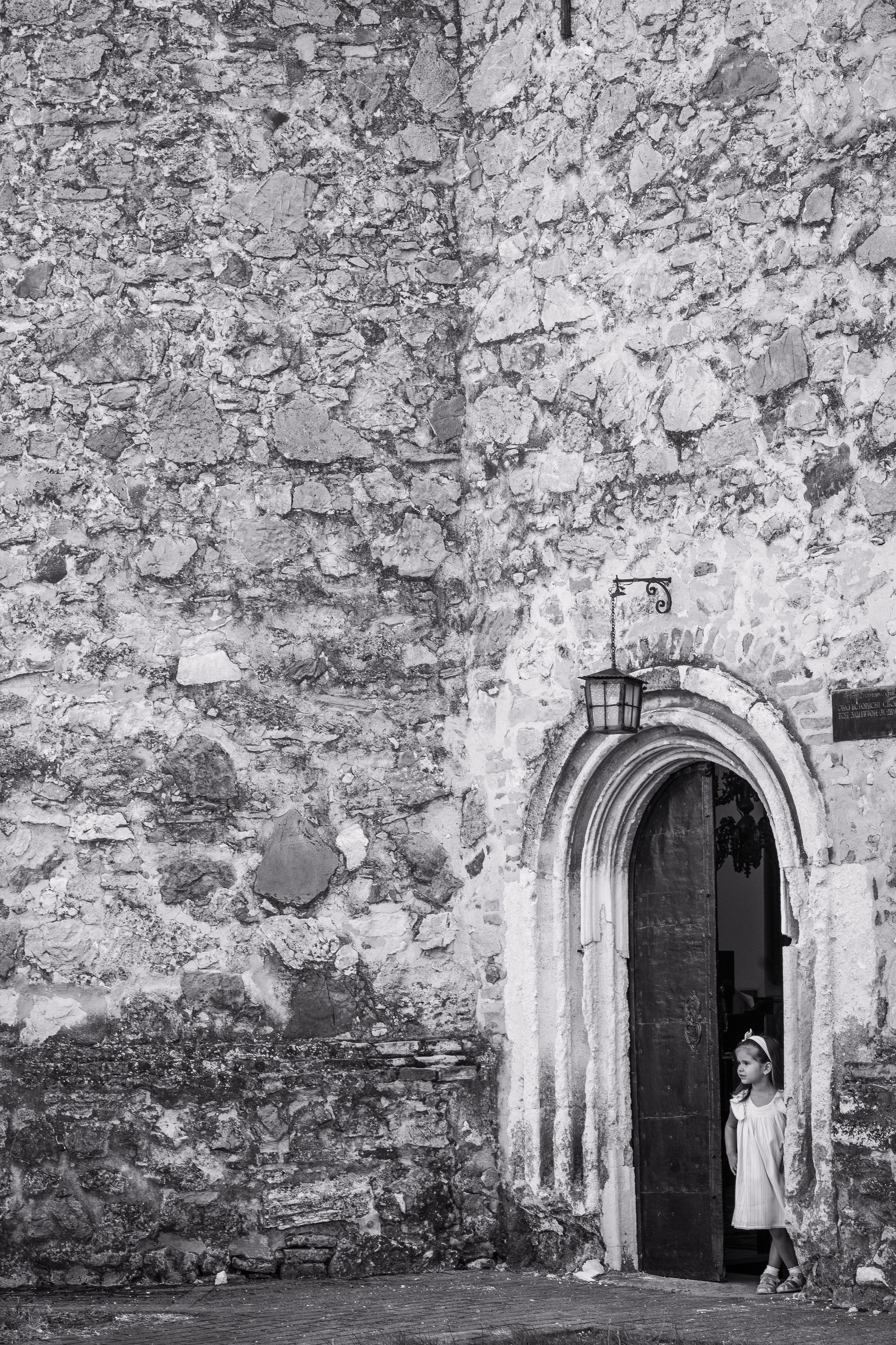 devojcica u svecanoj haljini stoji na vratima manastira