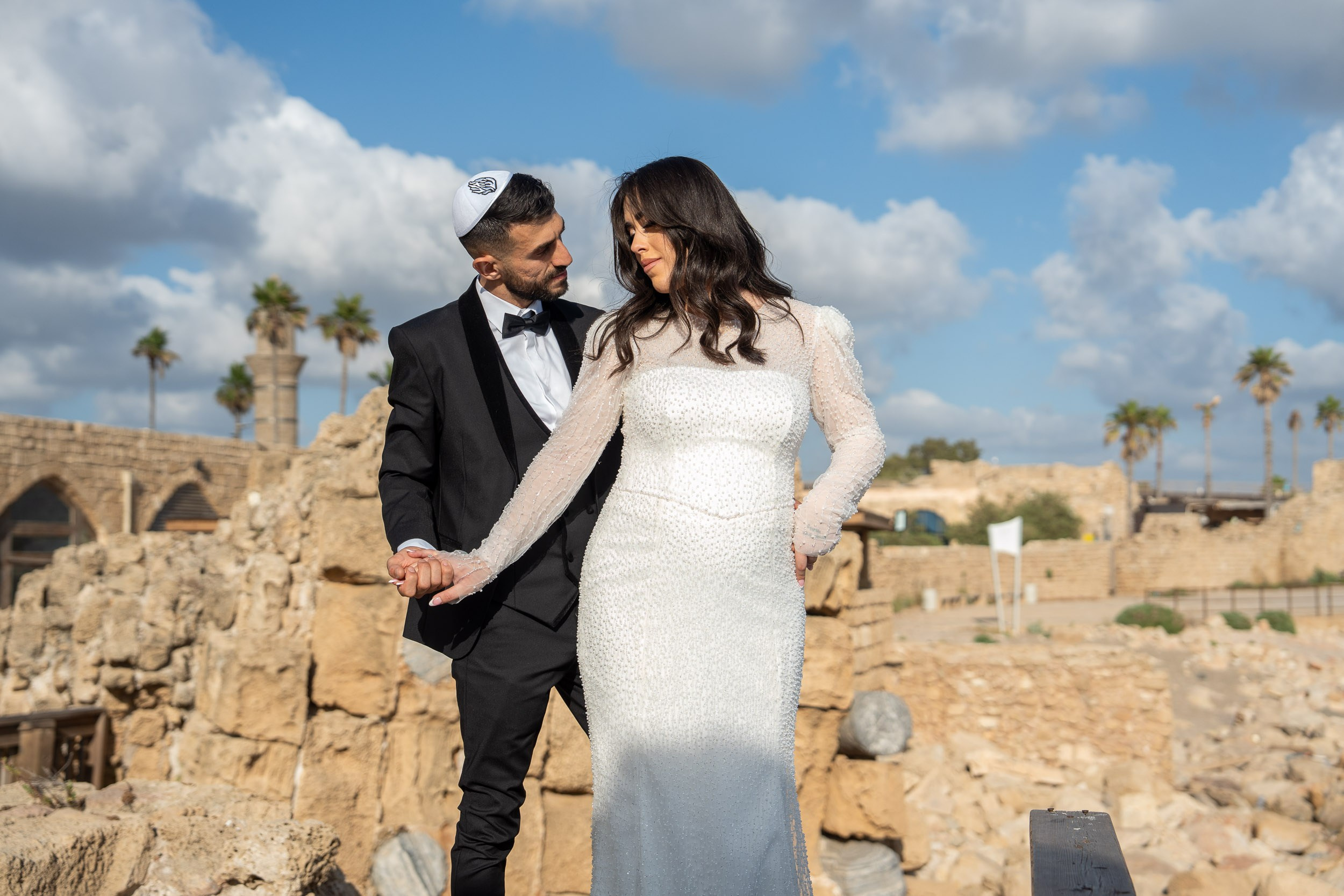 Bride Natali and groom Shimon holding hands near the ancient ruins during their photoshoot in Caesarea, Israel