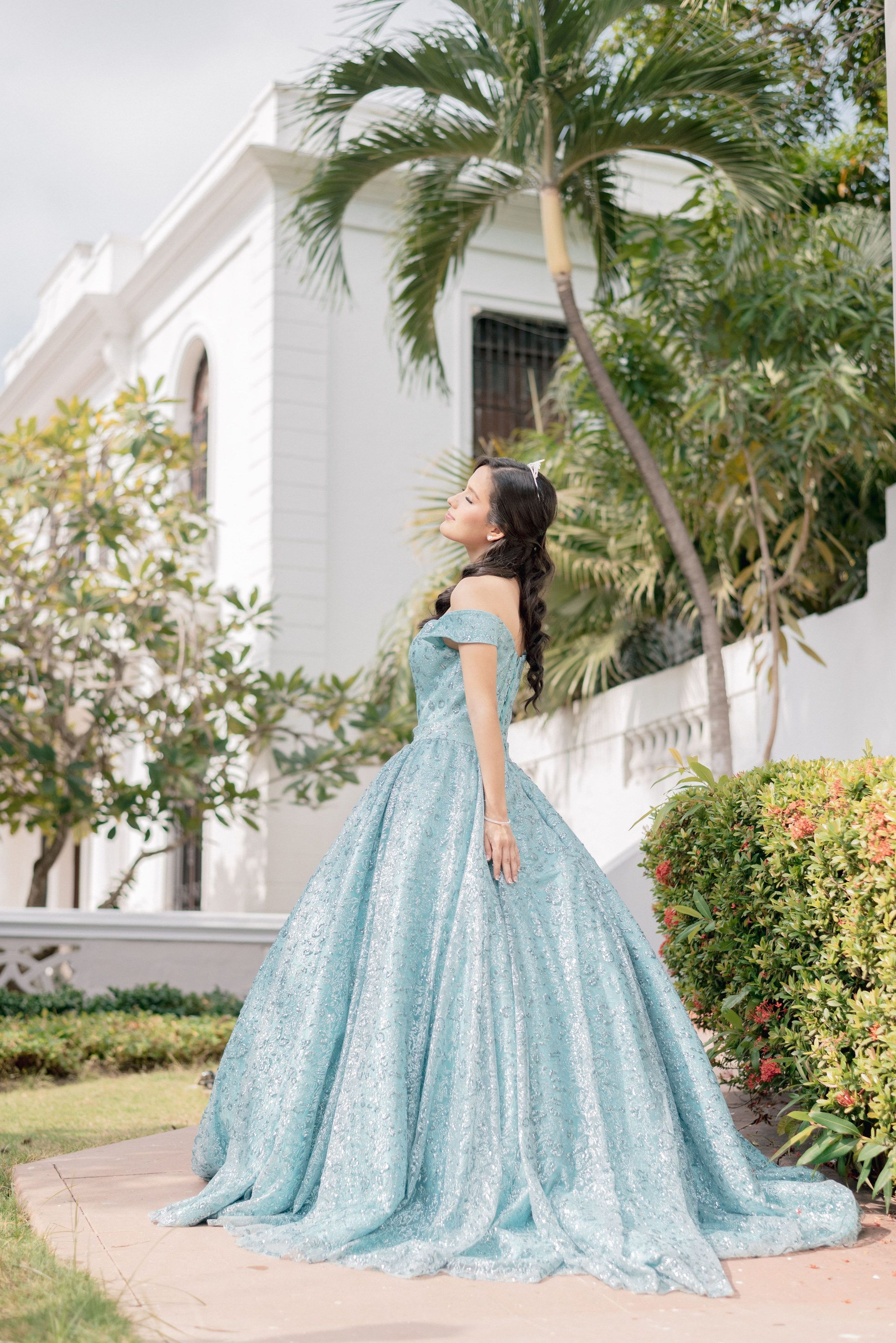 Fotografía de quince años tema princesa en jardín de Barranquilla, sesión artística de quinceañera con vestido azul y naturaleza, estilo de ensueño profesional Colombia
