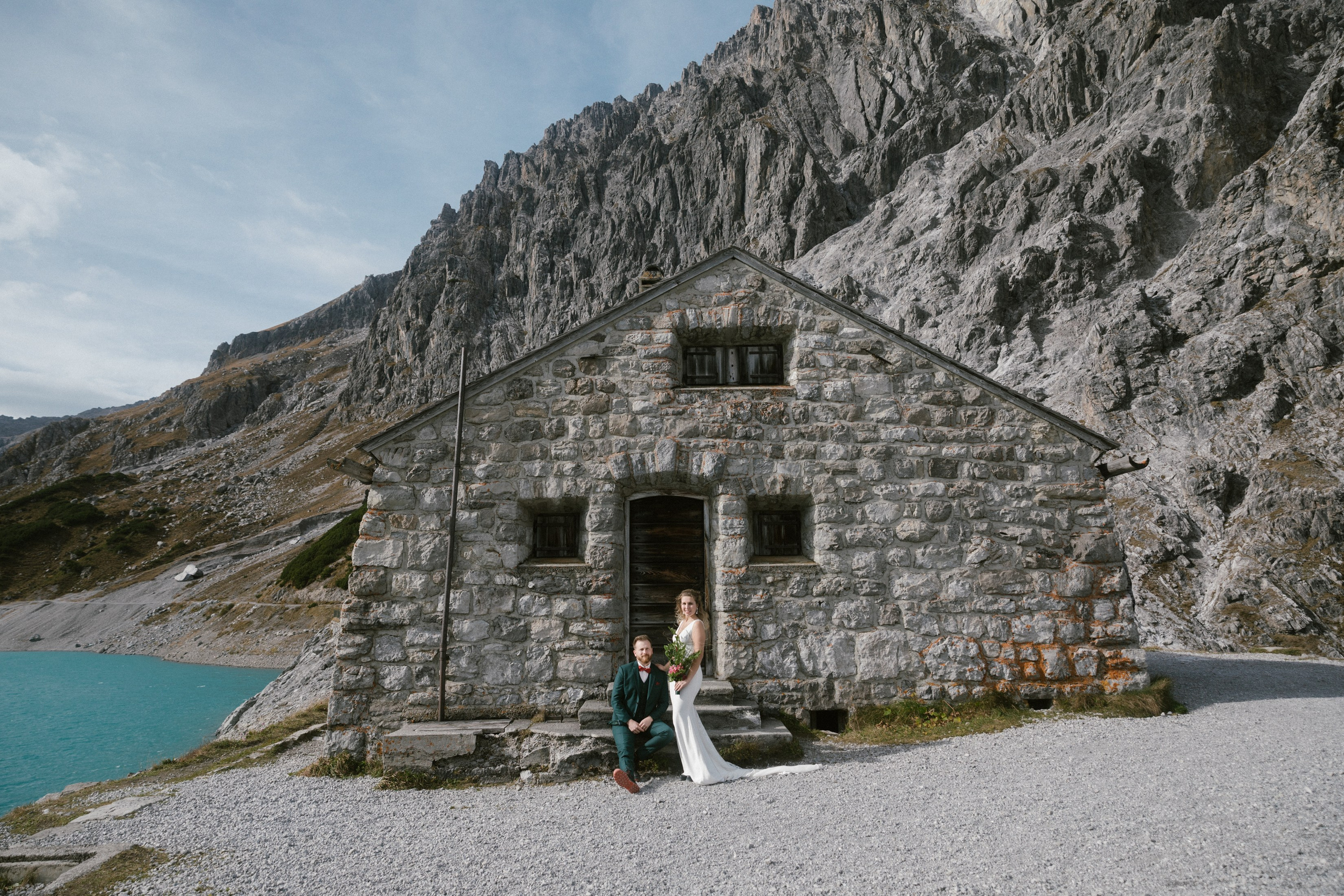 Hochzeitspaar vor rustikaler Steinhütte am Lünersee in den Alpen