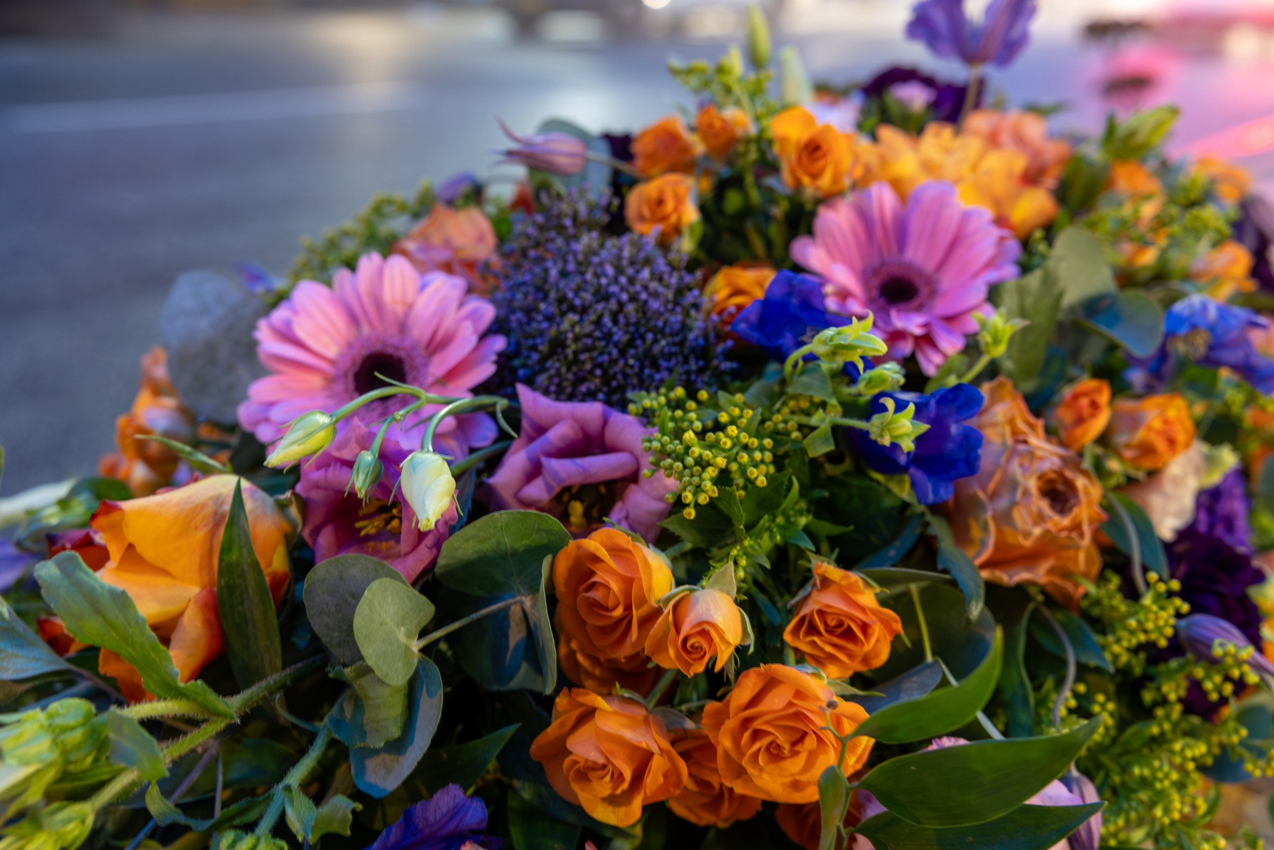 Kistepynt - Et eksklusivt farvel i hvid Farverig kistepynt med et let og levende udtryk. Blomsterstilkene har længde og højde, og fylder flot på kistelåget. Farverne er flot sammensat i stærke farver fra de orange toner over i pink-lilla nuancer. Kistepynten vil sætte farve på ethvert kirkerum. 