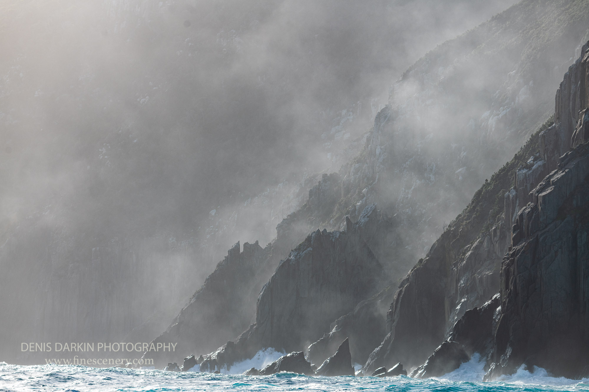 Cape Pillar vicinity, Dark coast of Tasmania (only being sunny a few weeks in the year), the outmost southern-bound shore looking directly at Antarctic continent. Powerful and cold southern ocean impact results in huge waves, bad climate and poor seafaring conditions. The fog in the shot is actually droplets of water from the rough wave action.