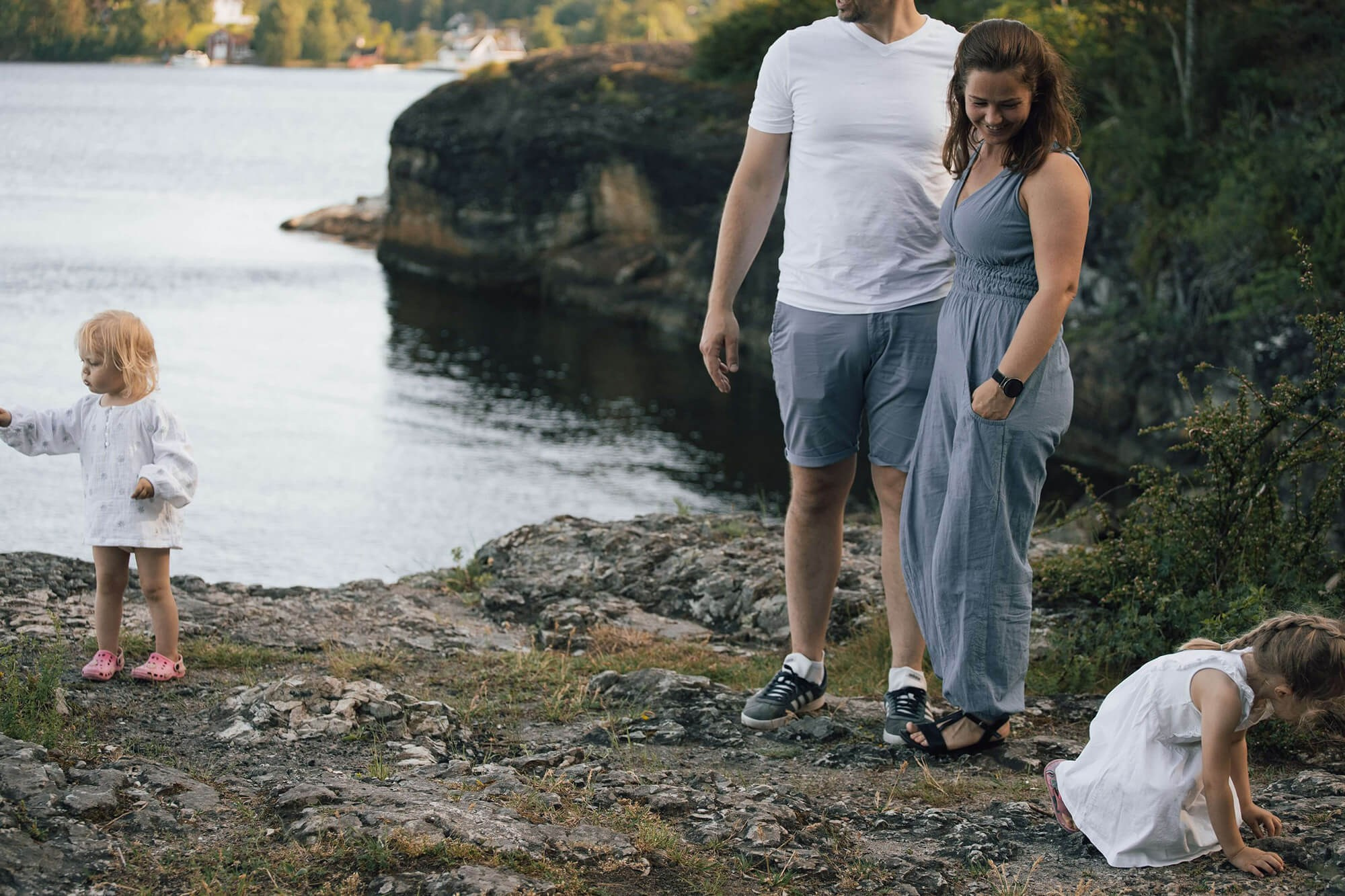 Mor og far smiler mens barna leker rundt dem