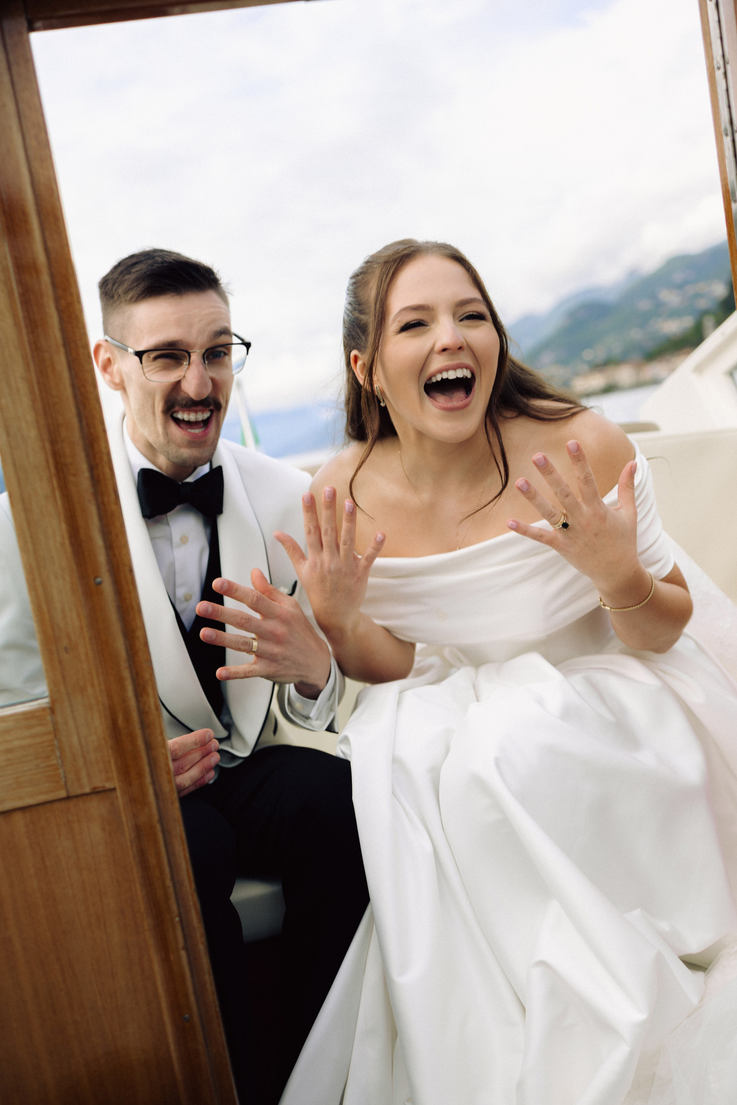 Bride and groom laughing together on a wooden boat on Lake Como