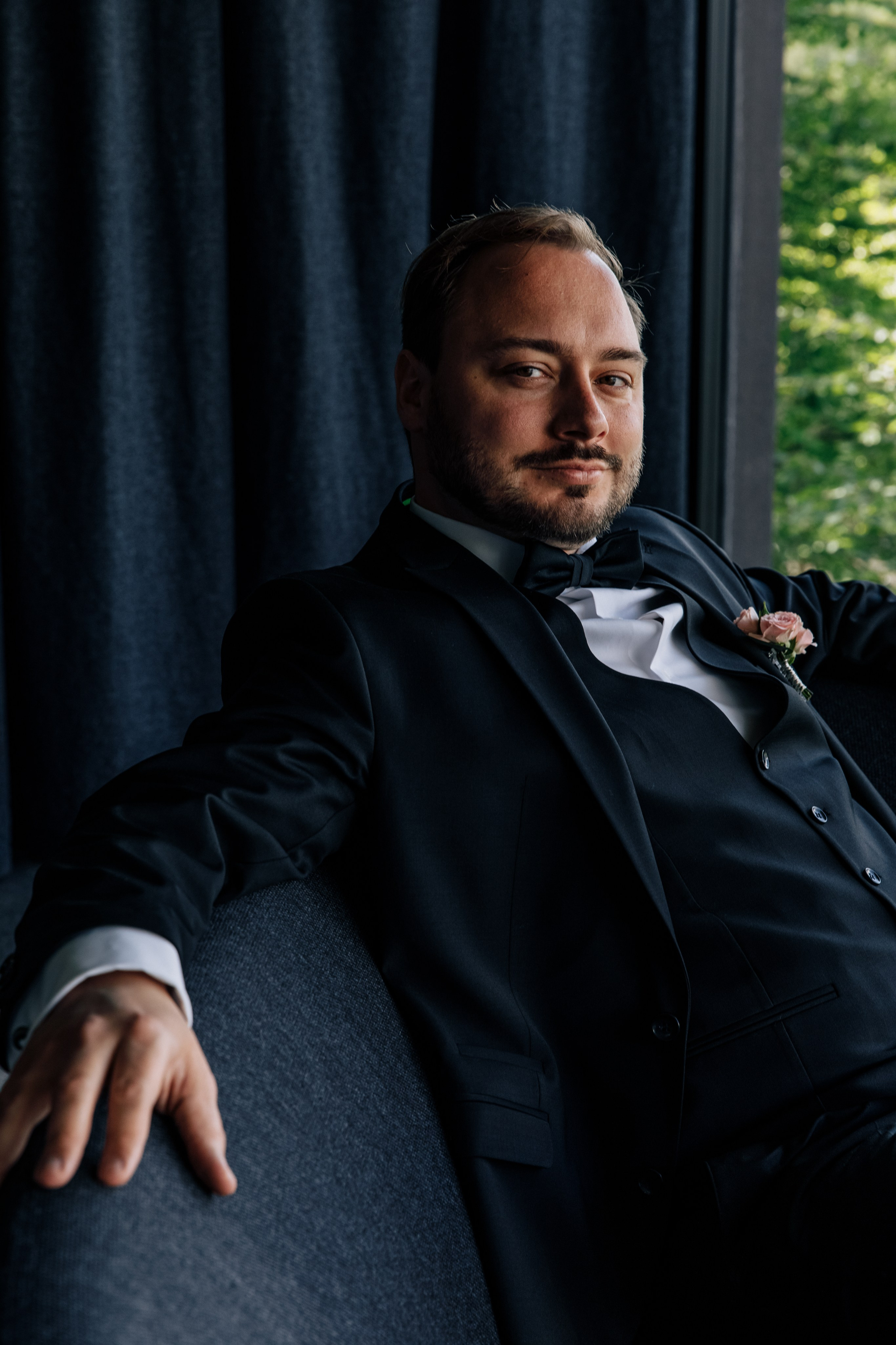 Der Bräutigam sitzt auf dem Sofa und schaut direkt in die Kamera.