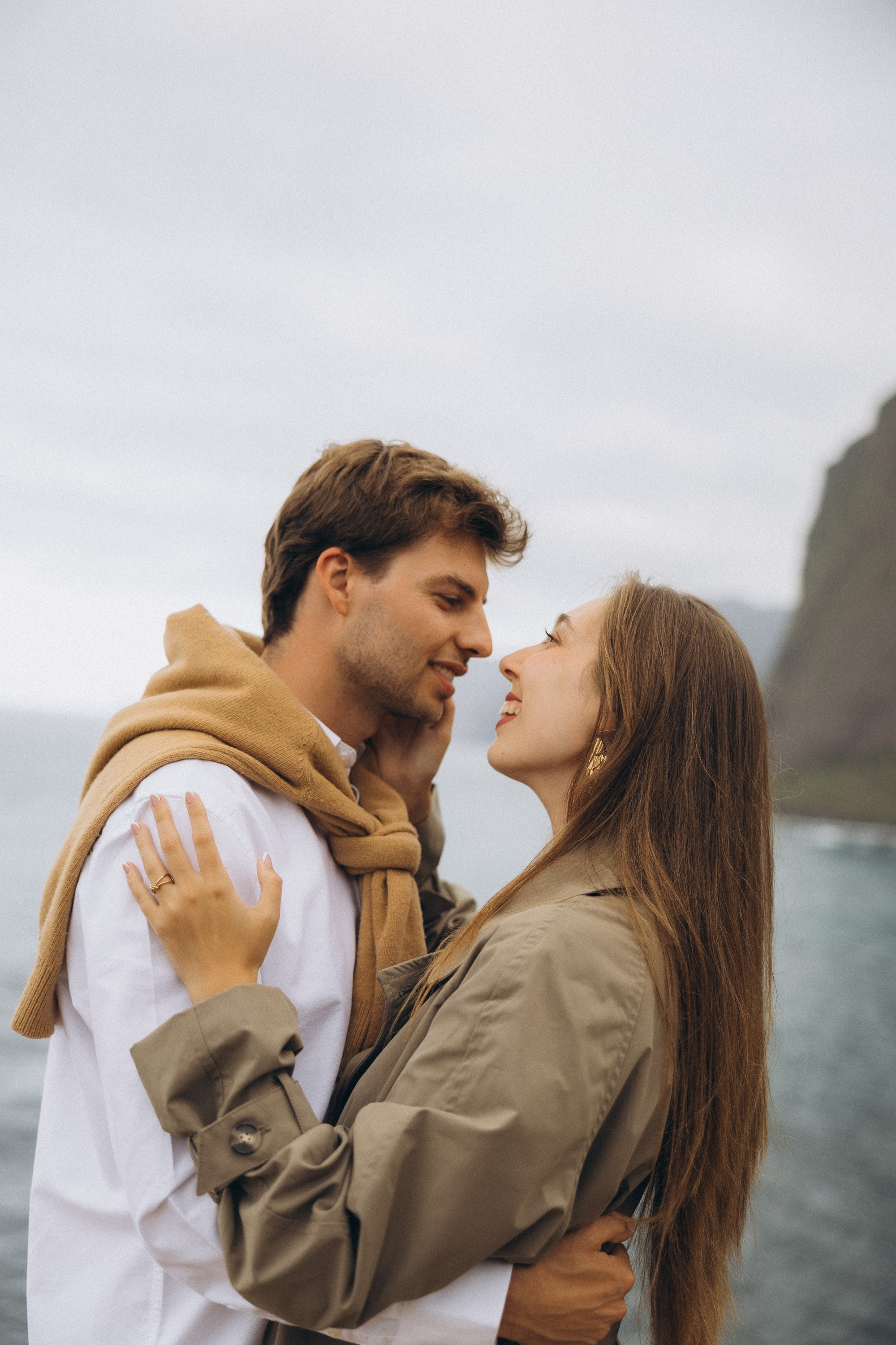 Beautiful engagement moment by the ocean in Madeira, Portugal, as one partner kneels to propose while waves crash in the background