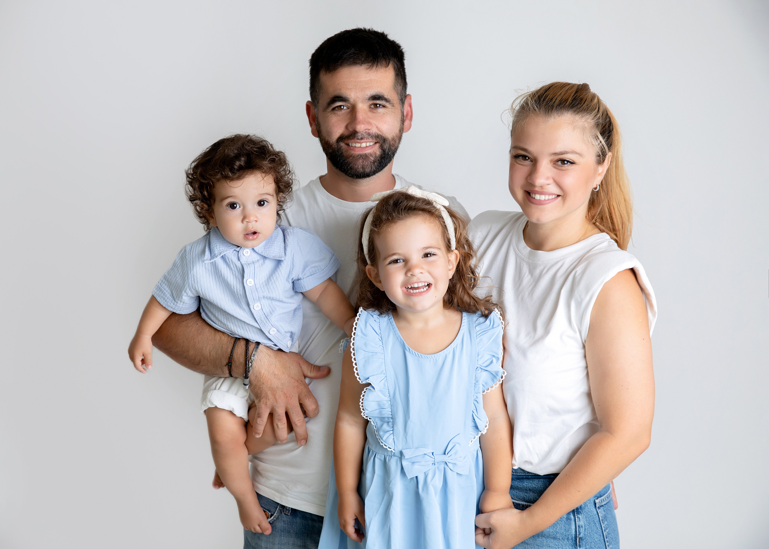 Familjefotografering i studion fångar ögonblicket av lycka med barn, mamma och pappa tillsammans.