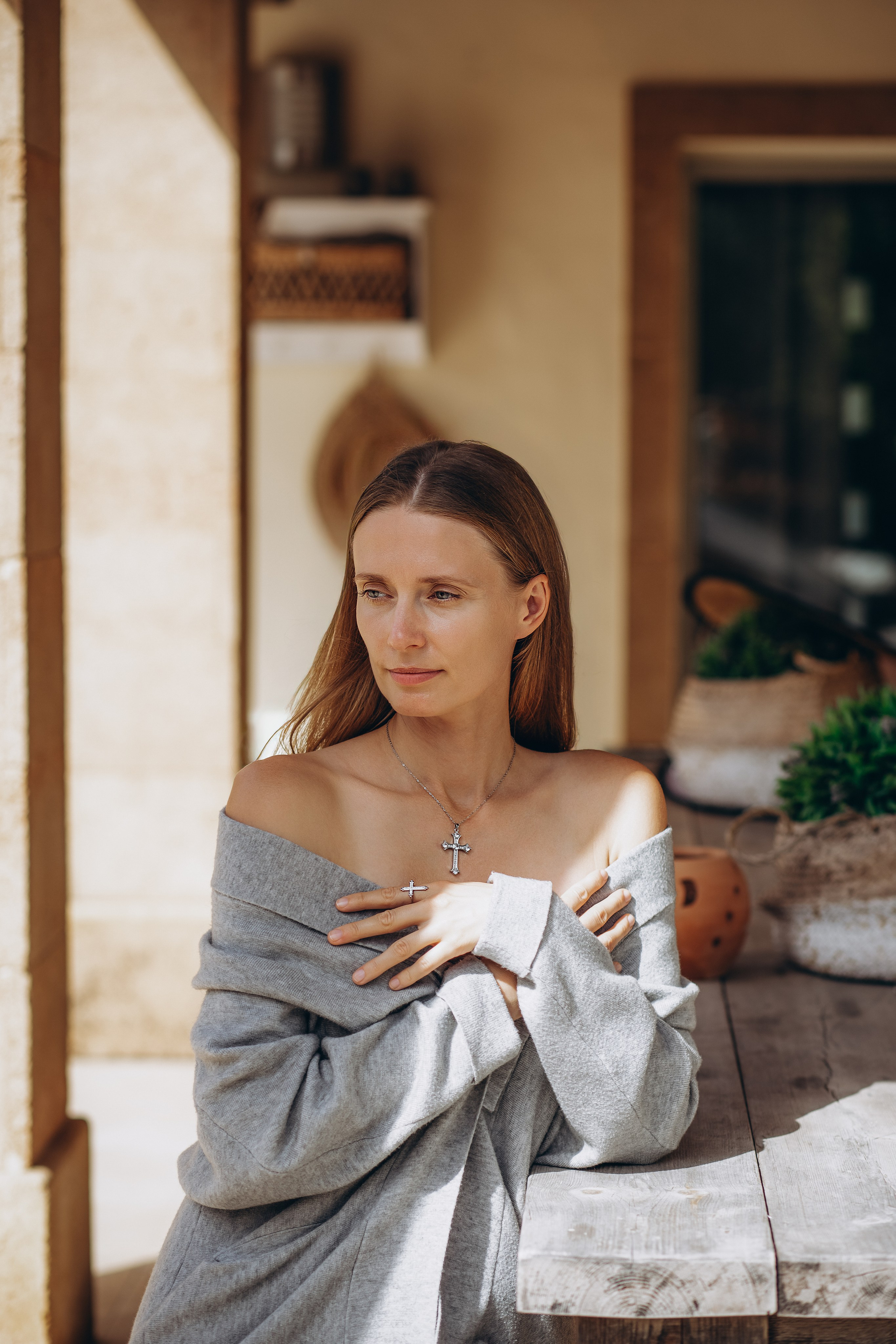 Elegant brand portrait of a woman in soft natural light, showcasing cross jewelry and relaxed fashion styling. Captured in Valencia, Spain, this image highlights minimalist branding and emotional storytelling — ideal for content creators or product photoshoots in Spain seeking timeless visual aesthetics.