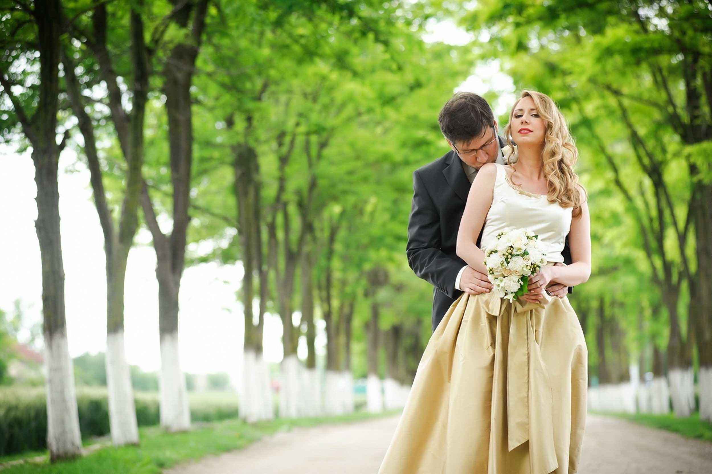 Romantičan poljubac mladoženje na tradicionalnom vojvođanskom salašu, uz prelepi drvored u pozadini